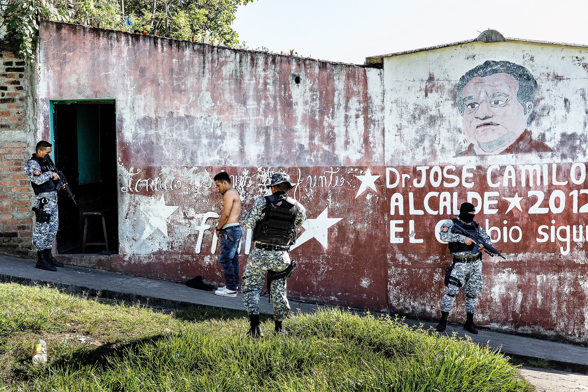 A tactical patrol checks a passer-by for weapons and identifying tattoos in the Apopa municipality of San Salvador