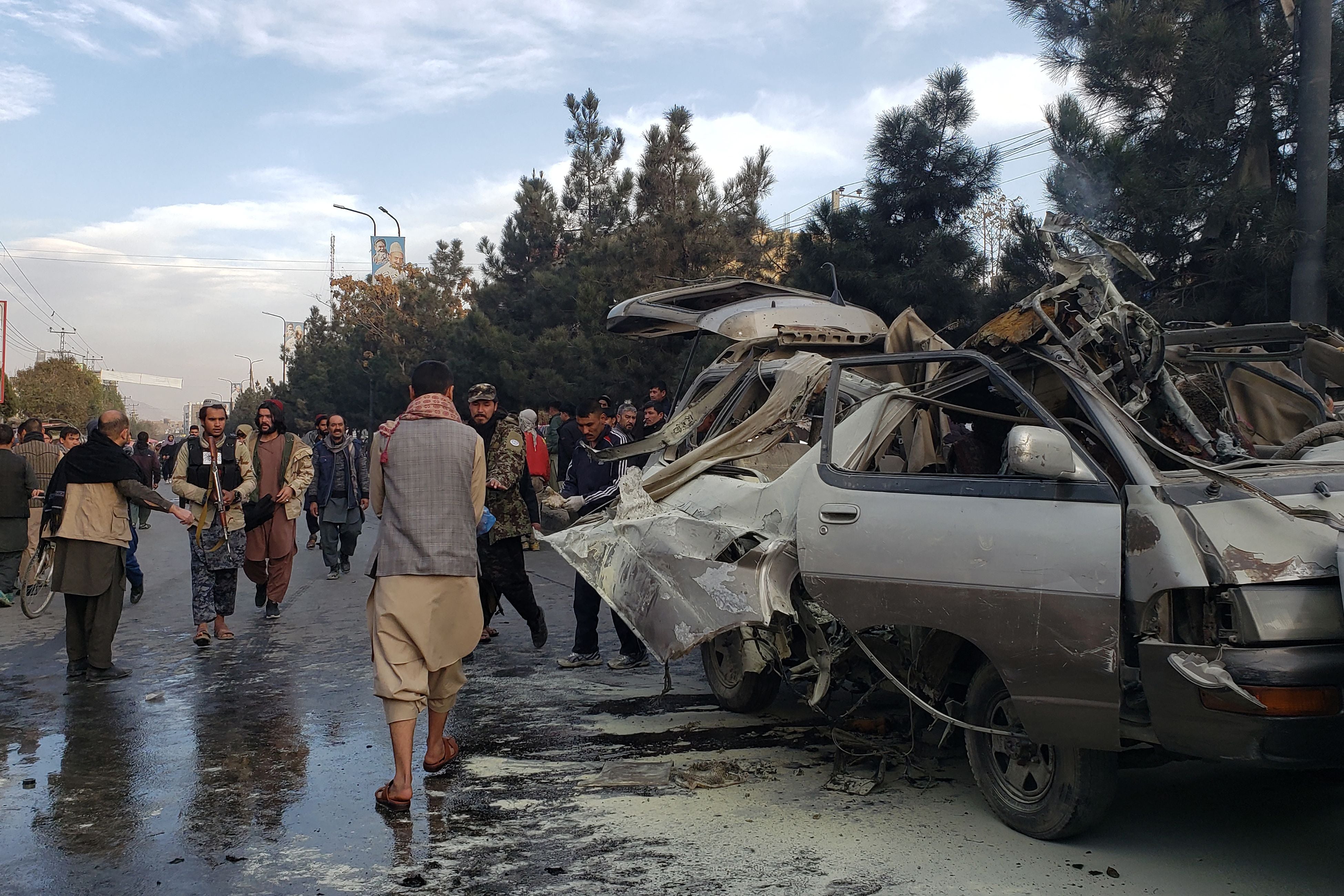 Residents gather next to a damaged minibus after a bomb blast in Kabul