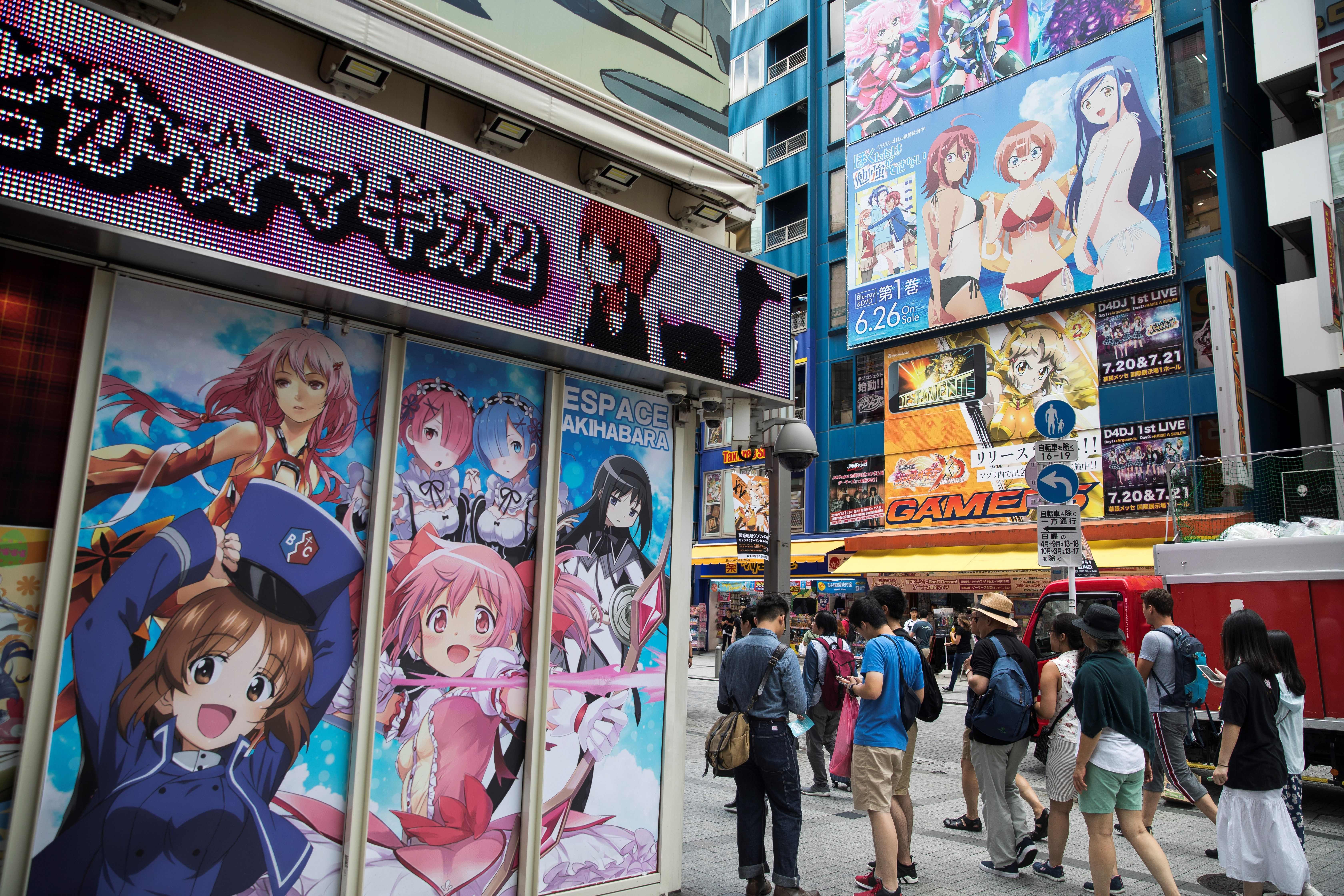 People walk past images of anime and manga characters in the Akihabara district in Tokyo