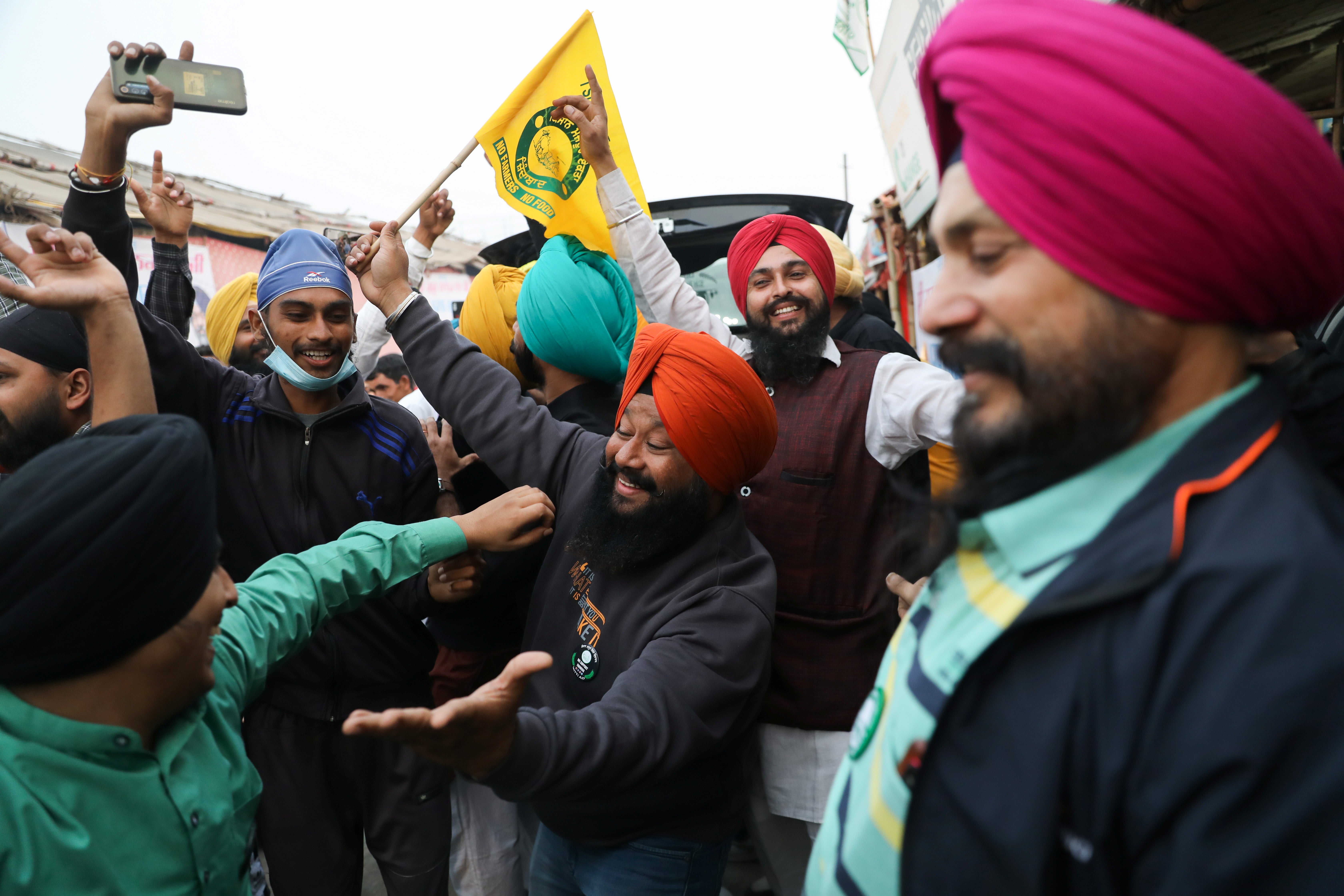 Farmers celebrate at the Singhu protest site near the Delhi-Haryana border