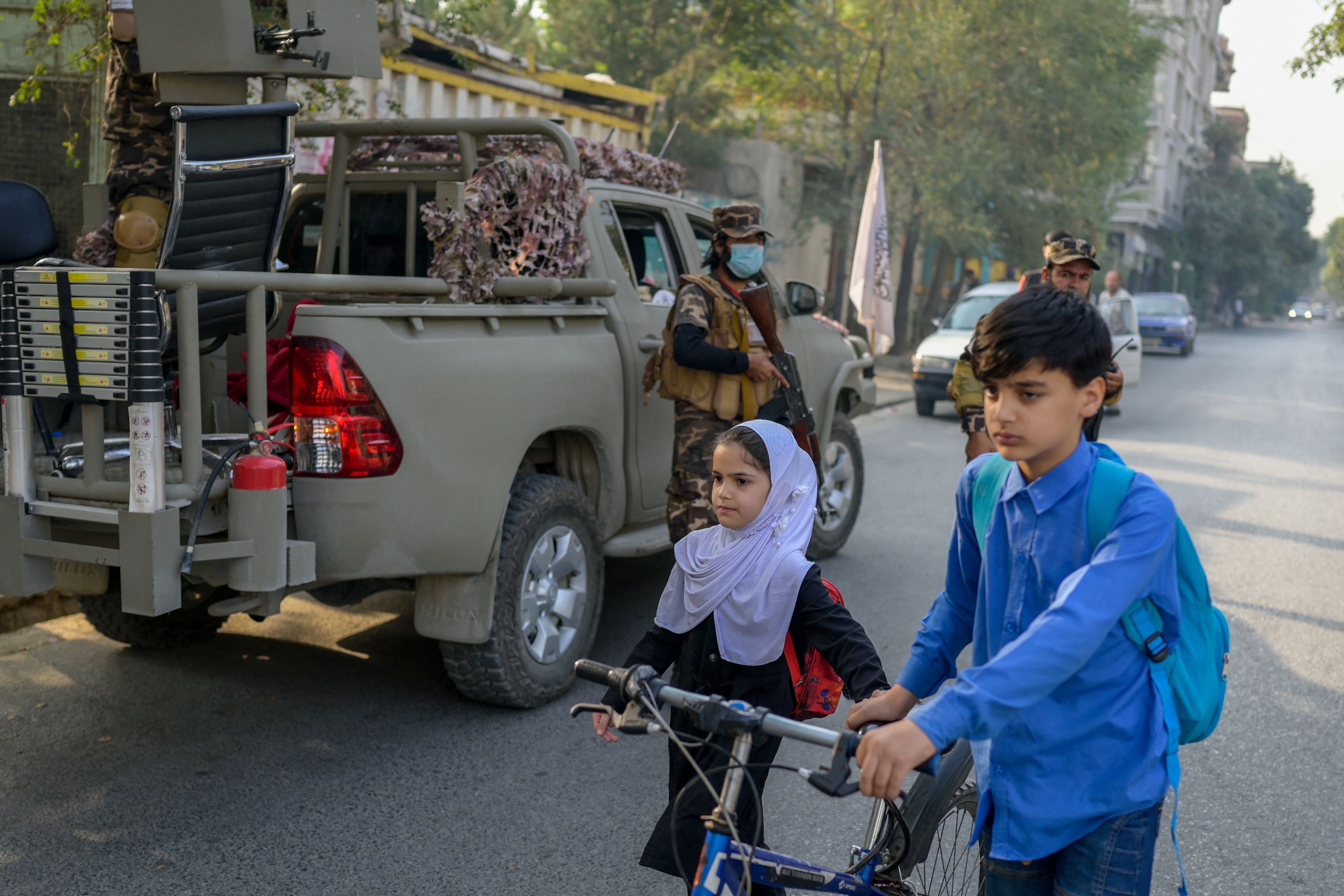 School pupils walk past Taliban special forces’ by a demonstration held by women in the capital of Kabul at the end of September