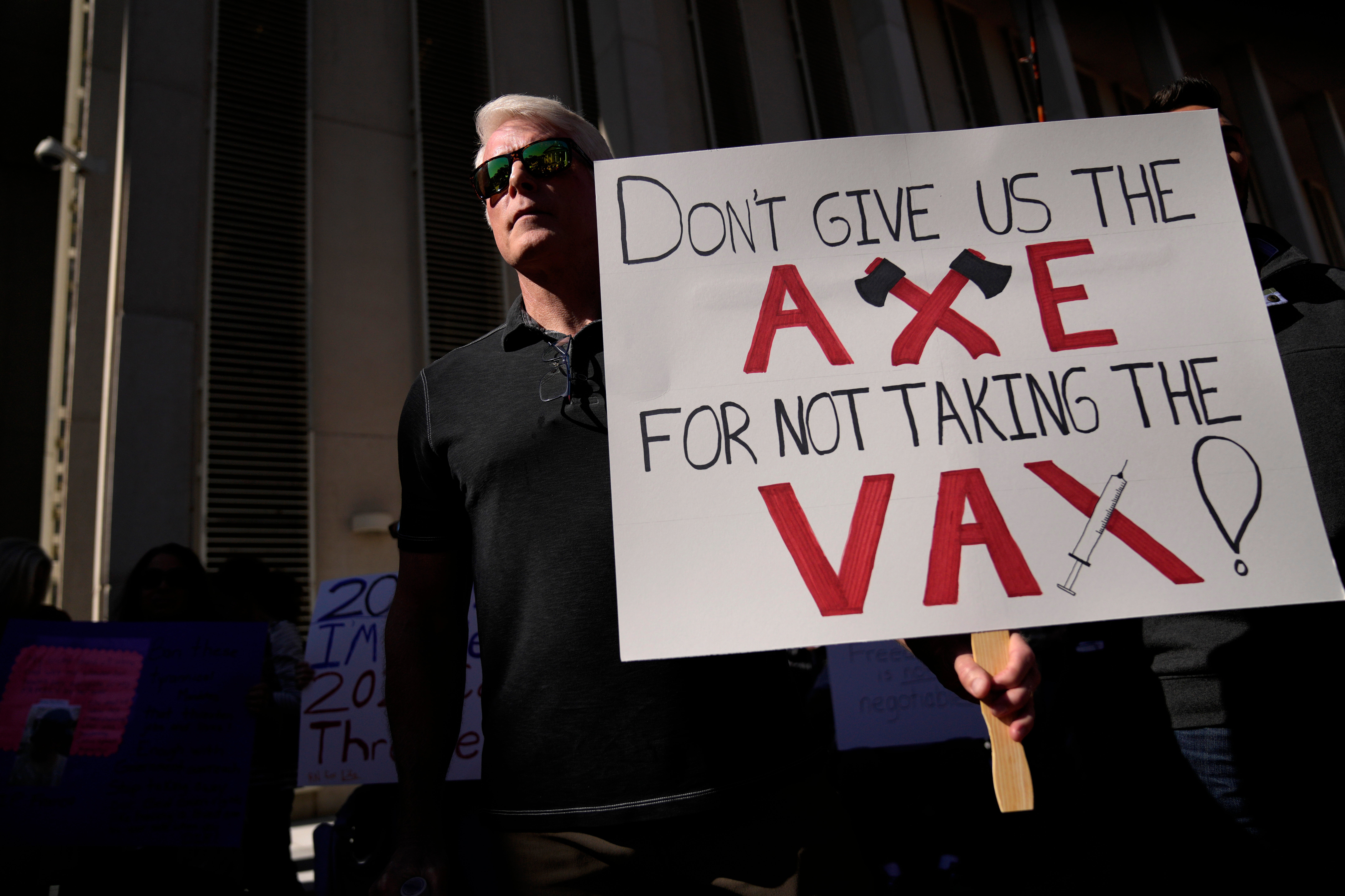 File: A man holds an anti-vaxx sign as hundreds of anti-mandate demonstrators had rallied outside the Capitol building on 16 November