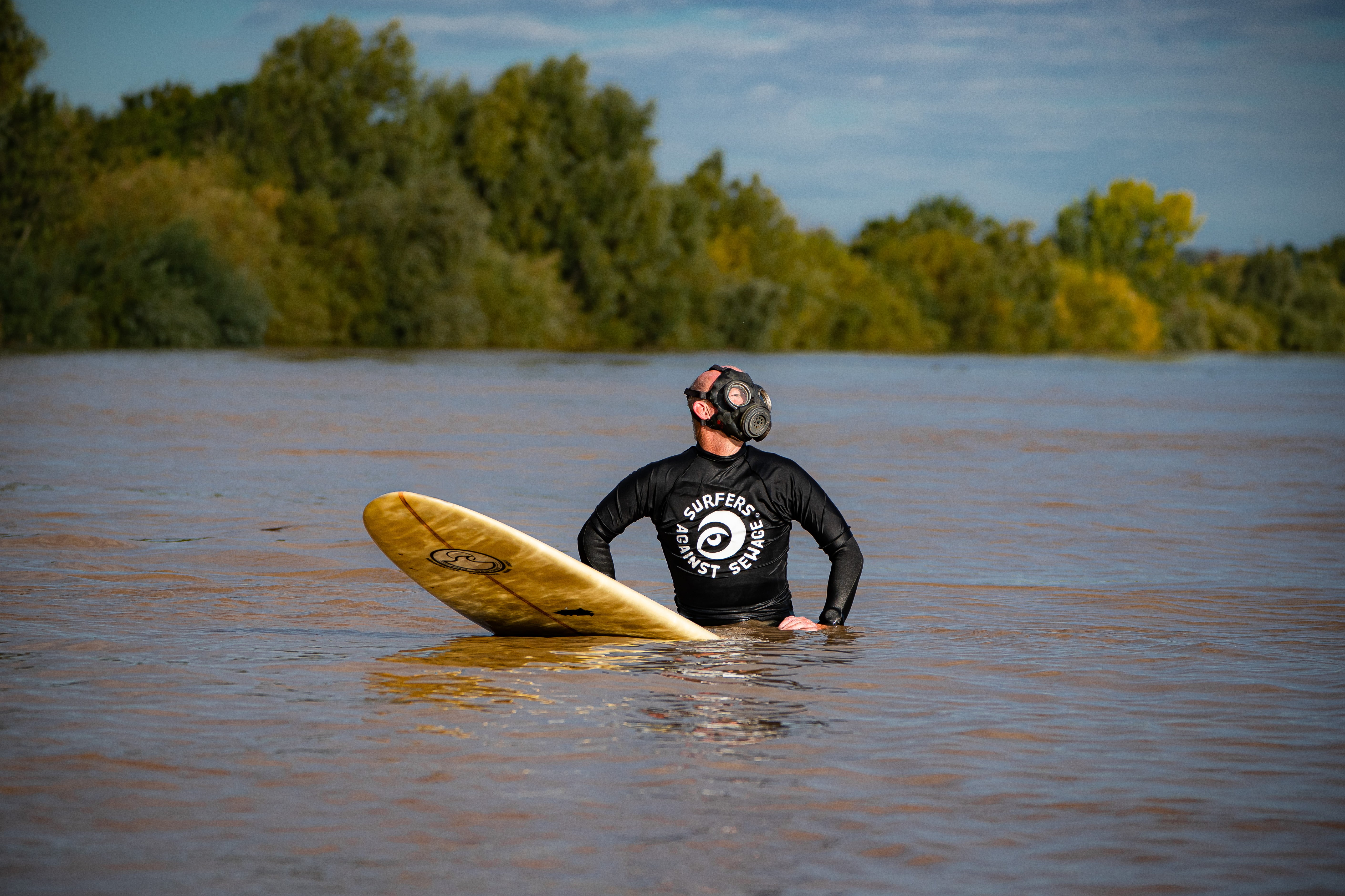 A Surfers Against Sewage activist prepares to surf the Severn Bore wearing a gas mask to raise awareness of sewage pollution