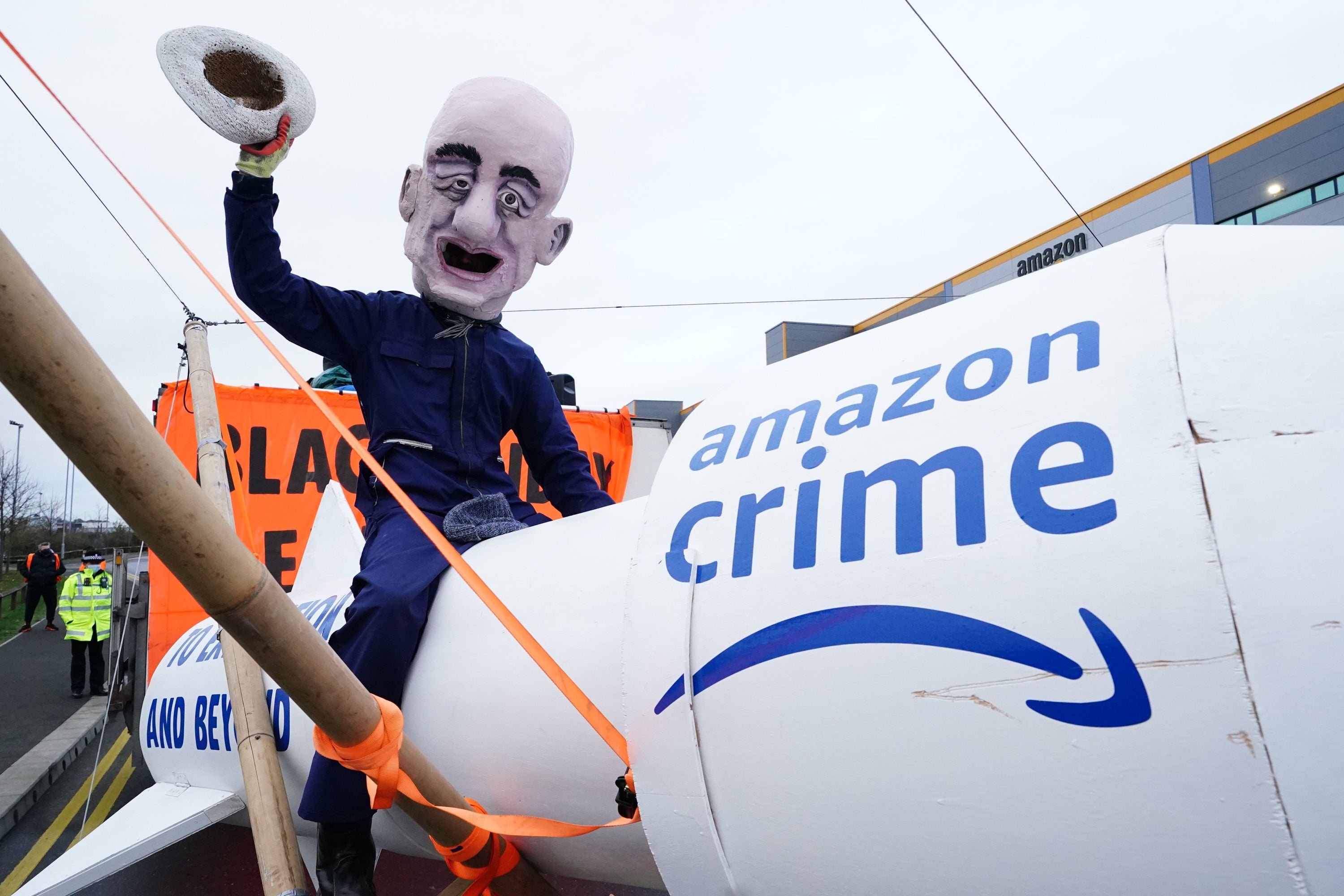 An activist from Extinction Rebellion, wearing a giant Jeff Bezos head, blocks the entrance to the Amazon fulfilment centre in Tilbury, Essex, in November 2021