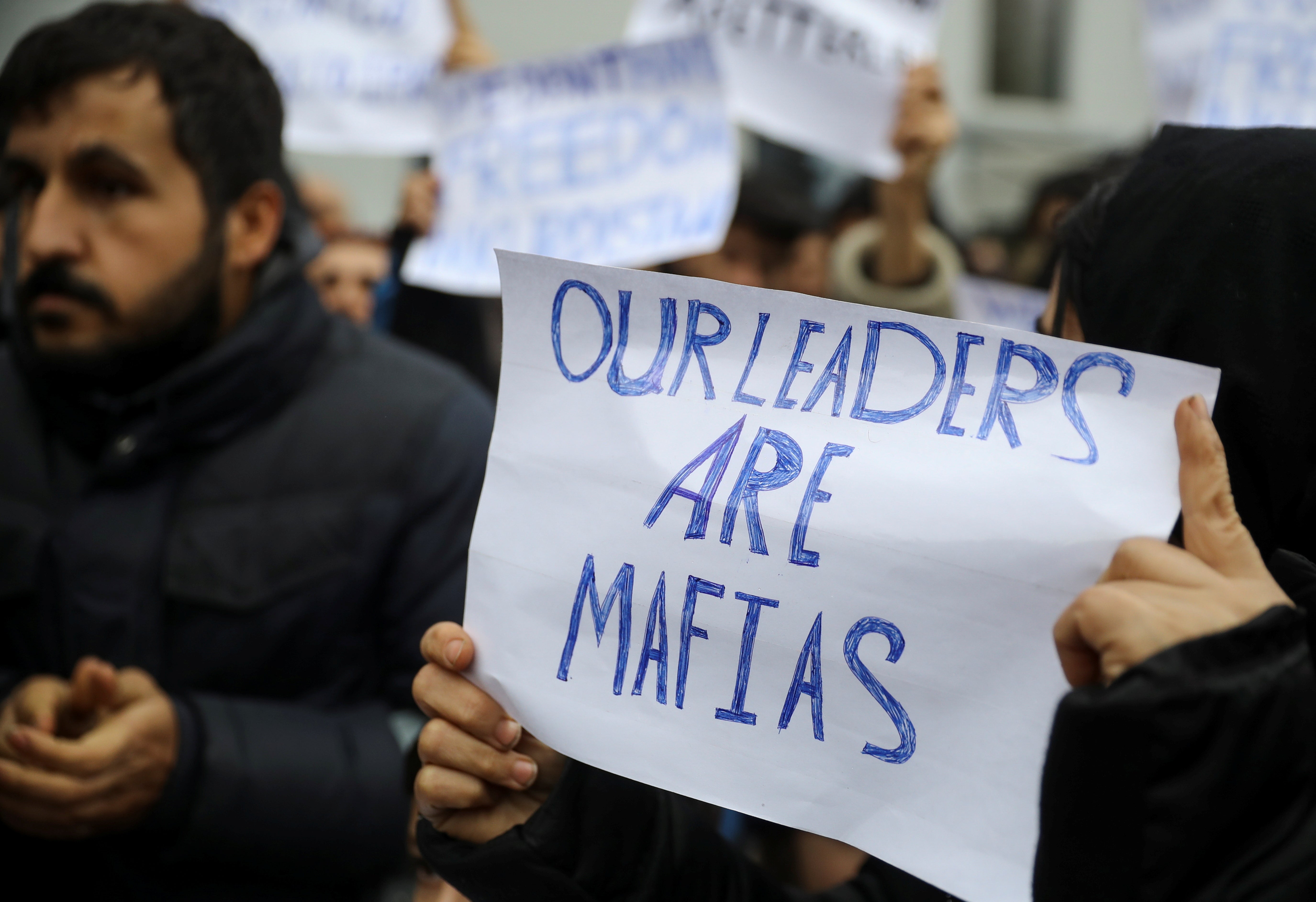 Migrants hold signs during a protest outside the transport and logistics centre in Bruzgi on the Belarusian-Polish border