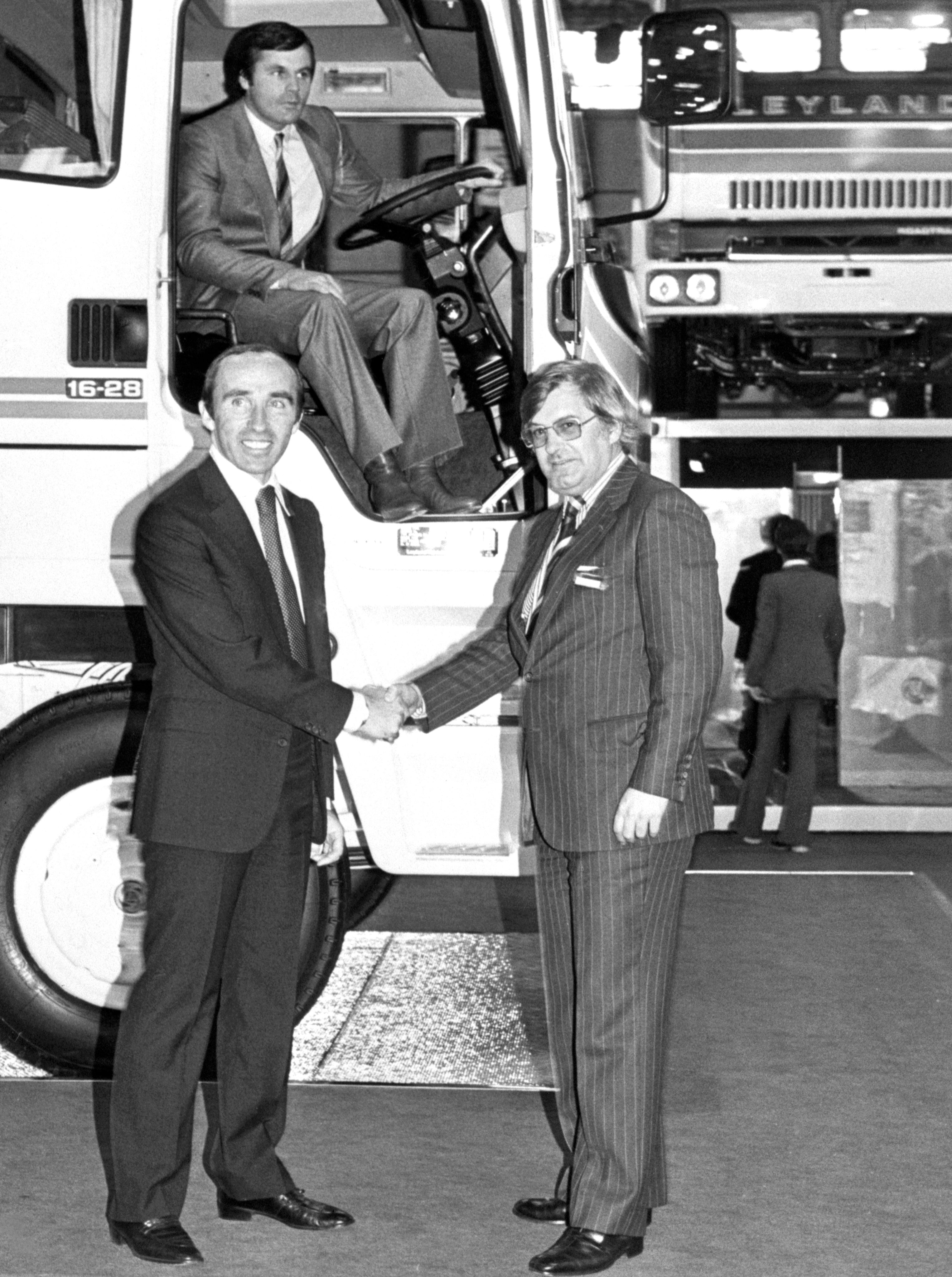 Williams, left, then the owner of the world championship-winning Saudia Leyland grand prix team, shakes hands with Frank Andrew, sales and marketing director of Leyland Vehicles Ltd (PA Archive)