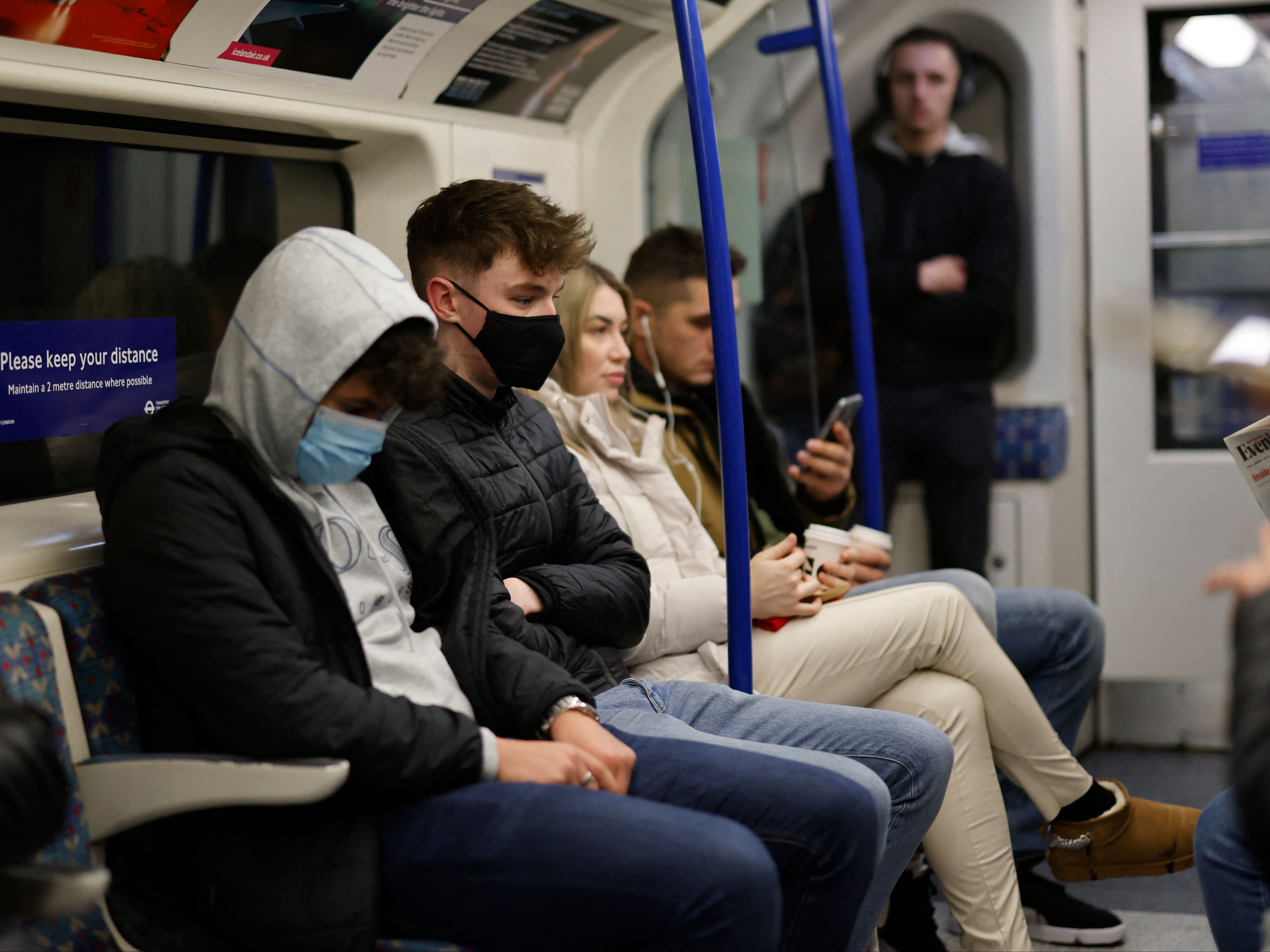 Passengers, some wearing face coverings, travel on the London