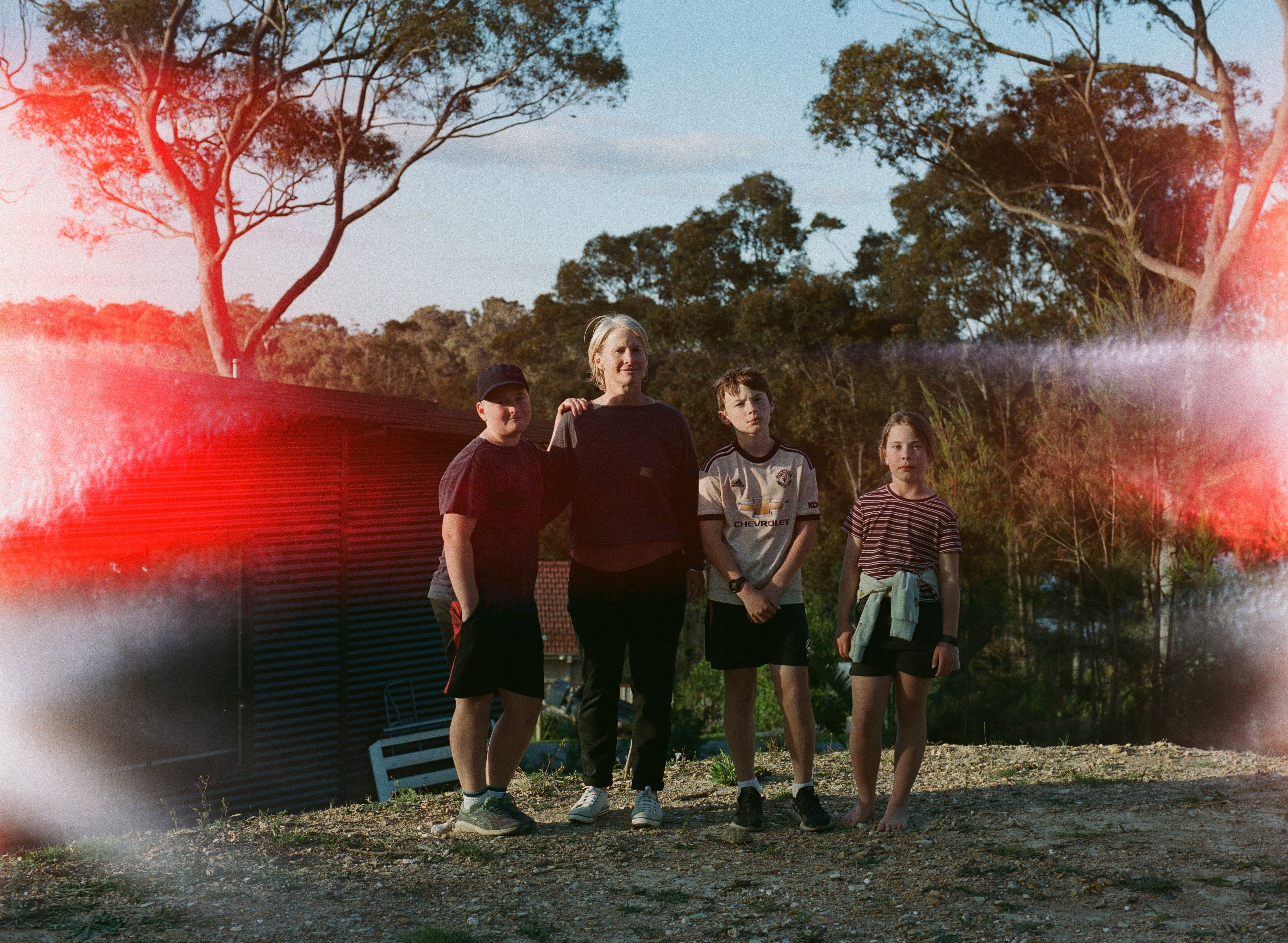 Harry with mum Margie and siblings Oscar, 13, and Romy, 9, in the backyard of their fire-damaged family home