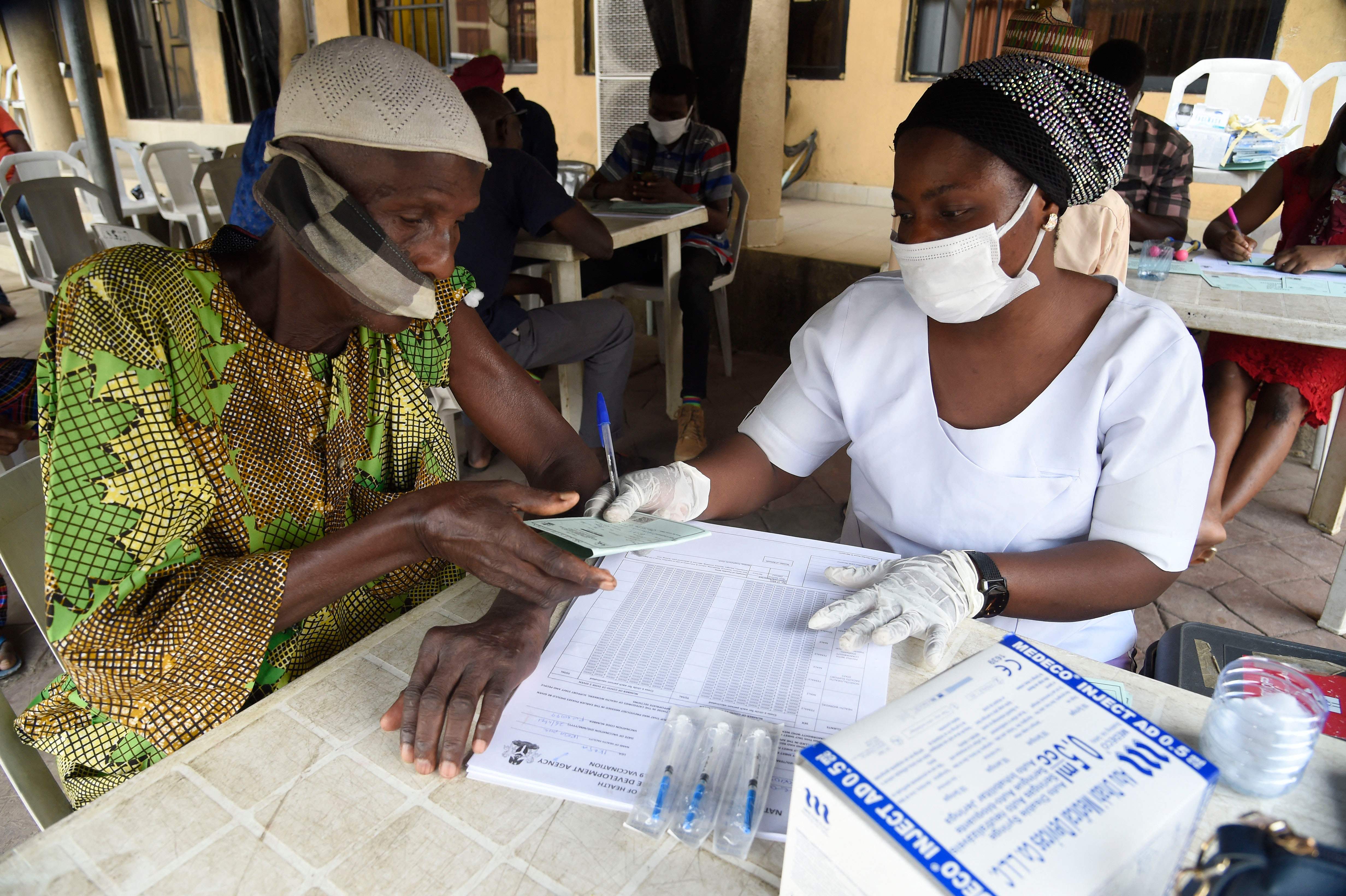 A man receives a vaccine card from a health official in Lagos, Nigeria