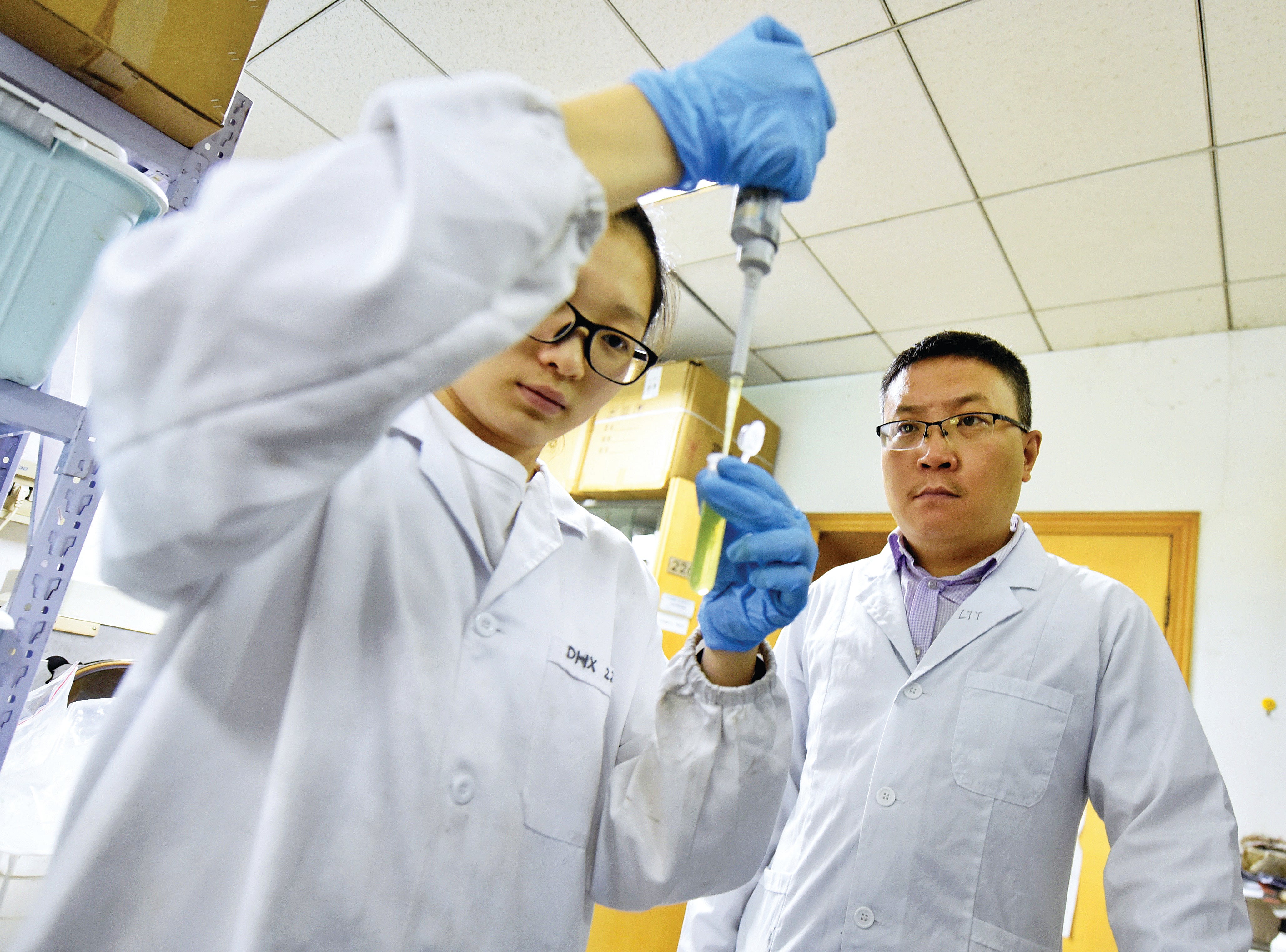 A researcher (right) and his assistant wait for test results of organic waste resources at a unit of the Chinese Academy of Sciences in Chengdu, Sichuan province