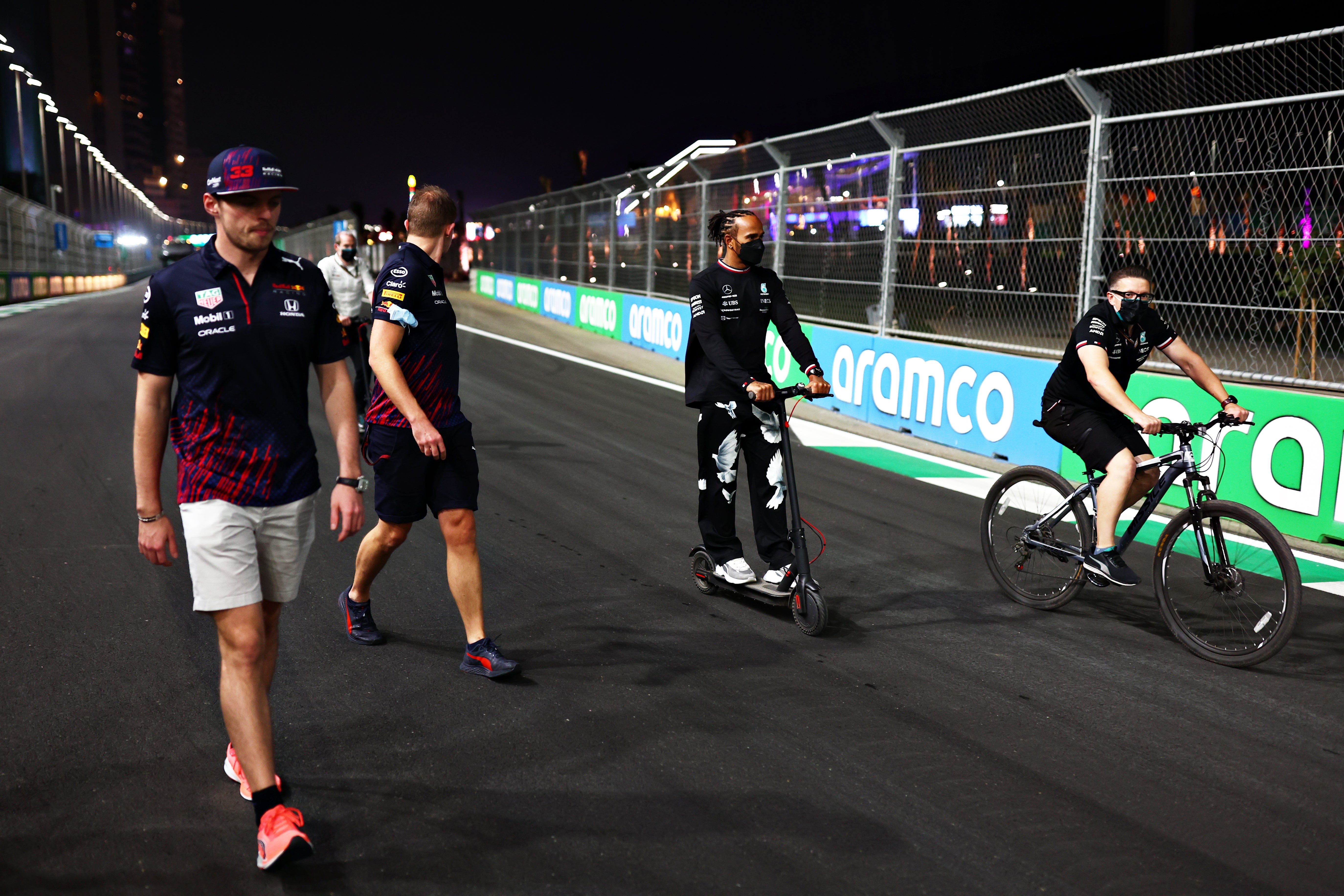 Max Verstappen, left, and Lewis Hamilton, centre, walk (or ride) the track