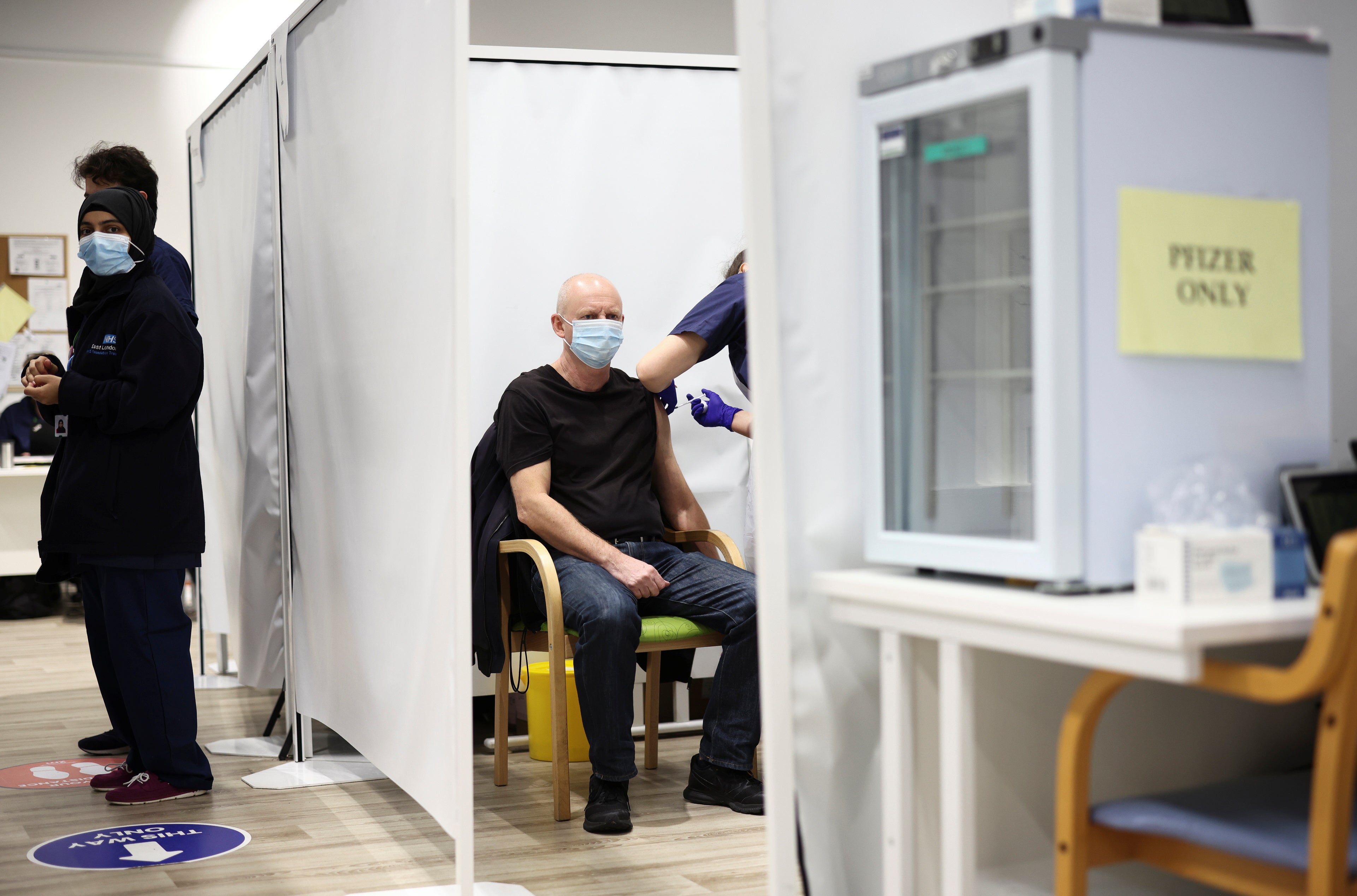 A person receives a dose of the Pfizer coronavirus disease (COVID-19) vaccine at a vaccination site at the Westfield shopping centre in London.