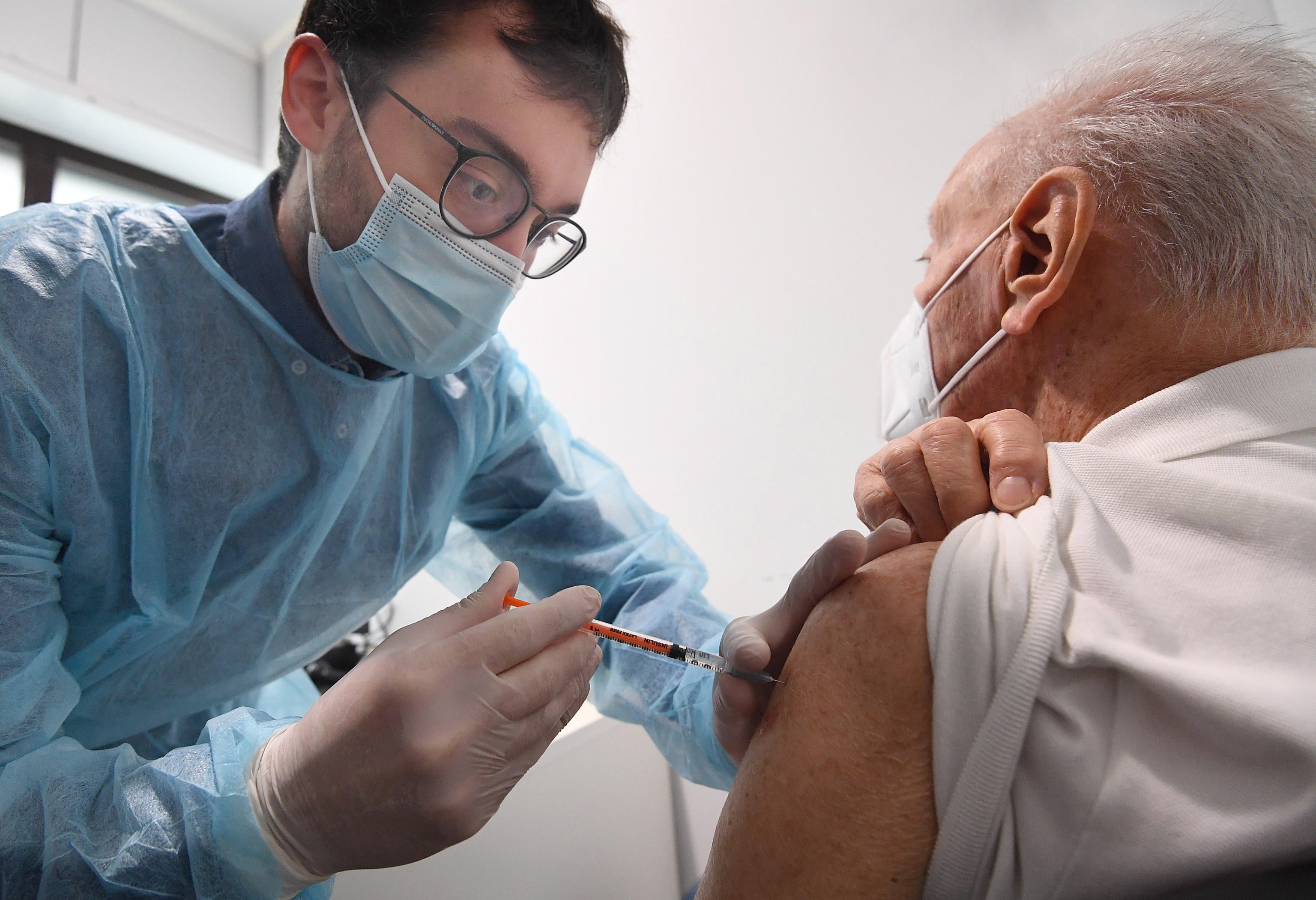 A pharmacist administers the third dose of Pfizer-BioNTech COVID-19 vaccine to an elderly person in a pharmacy in Milan, northern Italy.