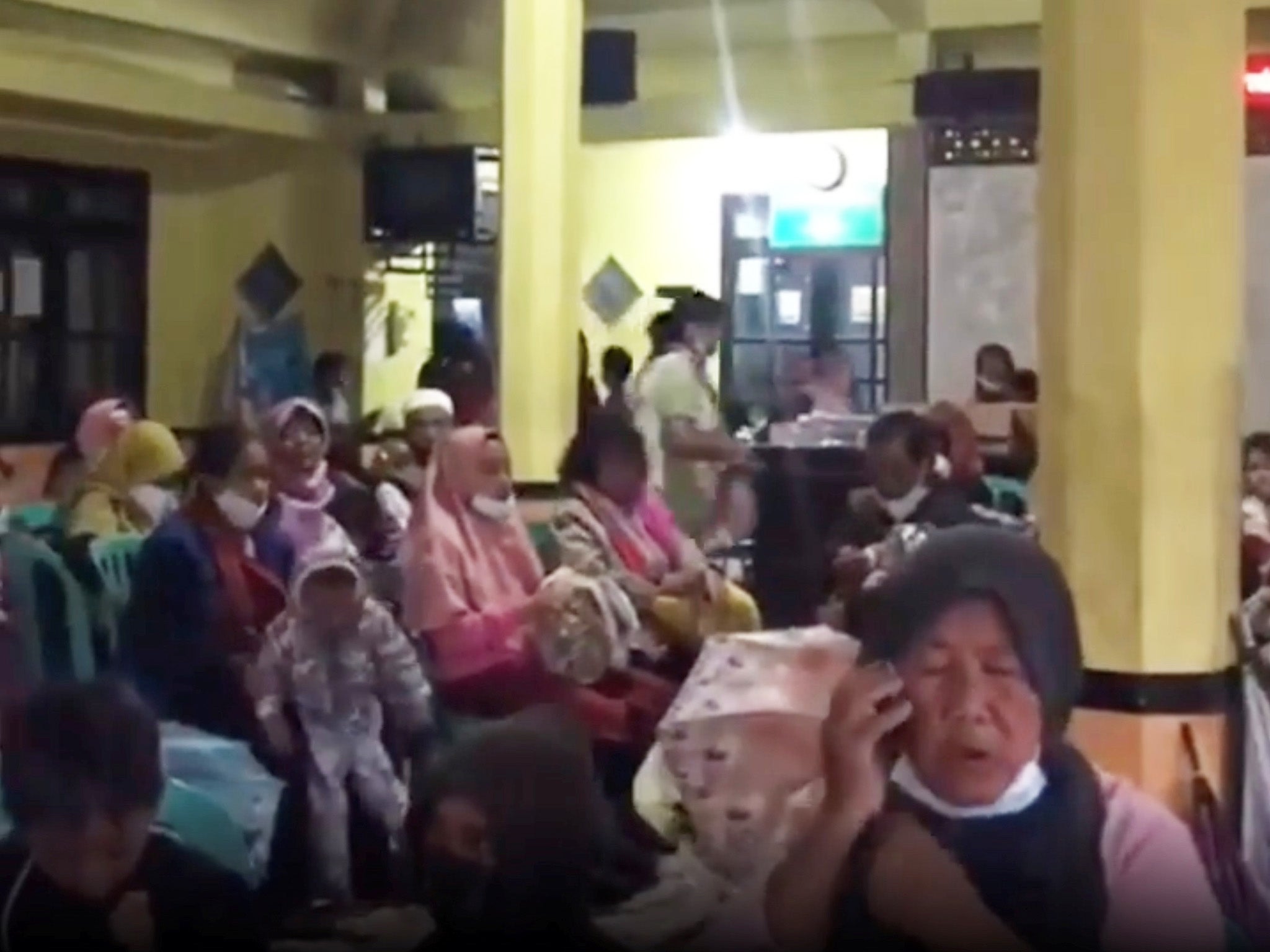 People wait at an evacuation center in Candipuro near the foot of the mountain