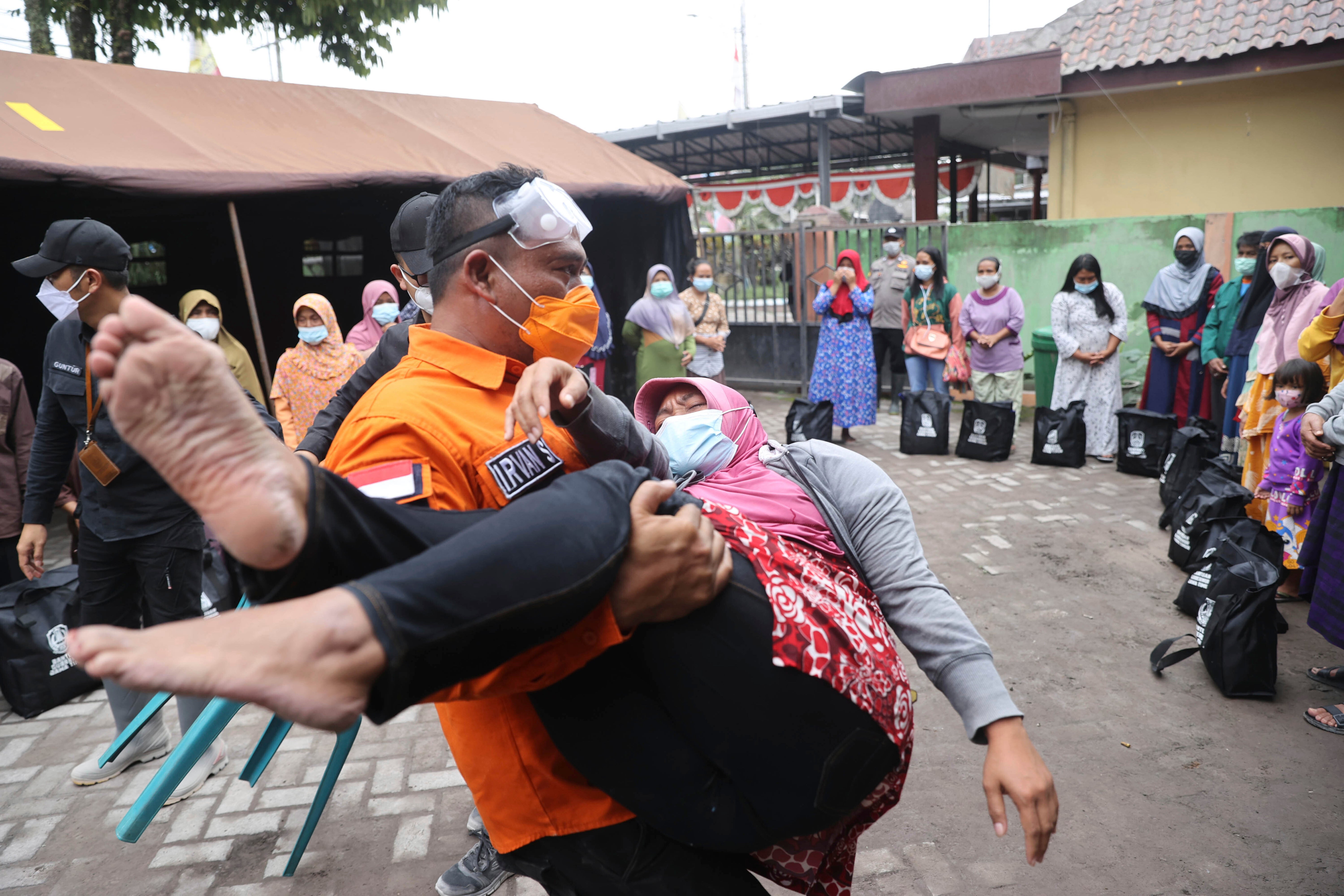 A rescuer carries a woman who fainted after the eruption of Mount Semeru