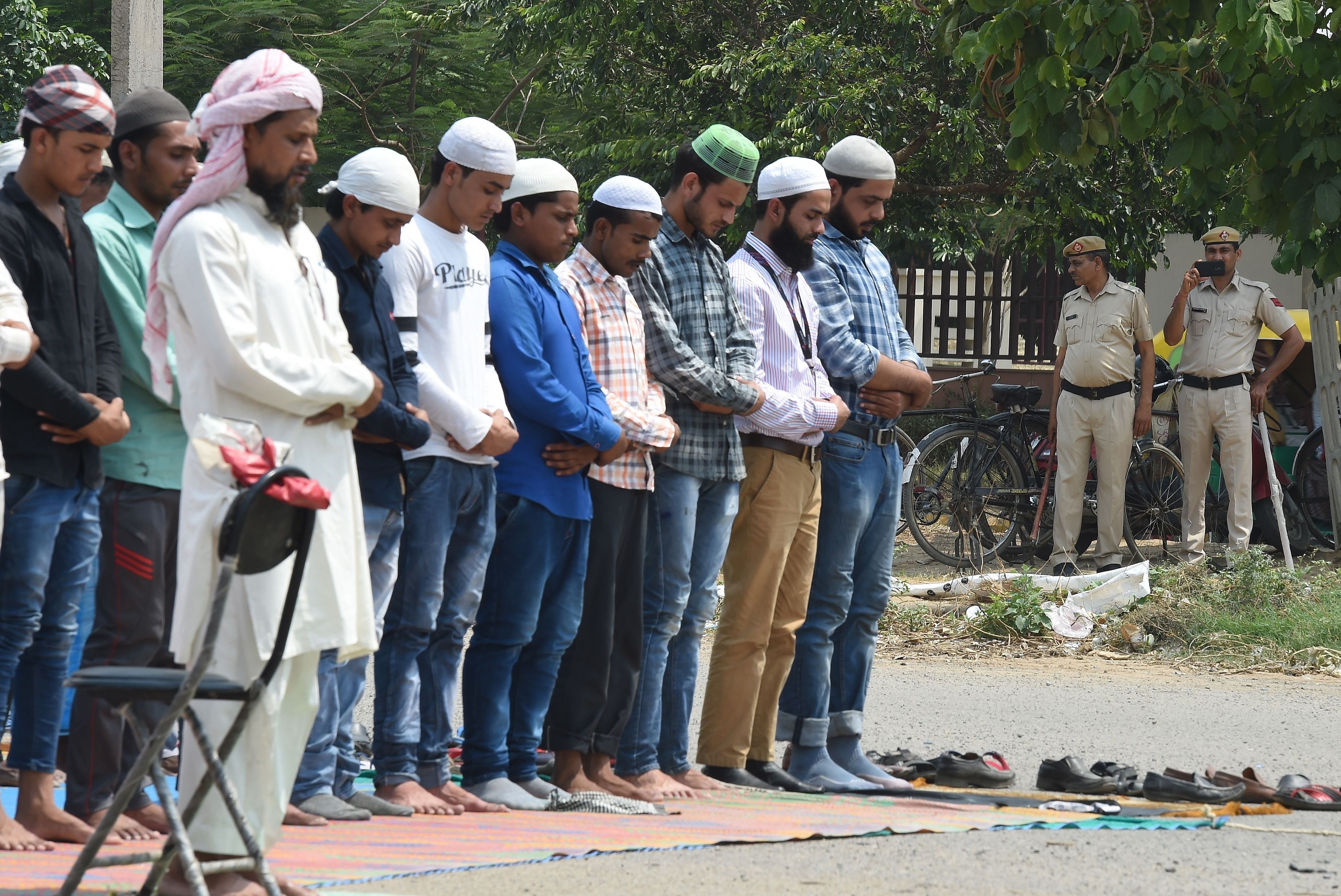 Indian police stand guard as Muslims offer Friday prayer in a open car parking area in Gurugram in May 2018