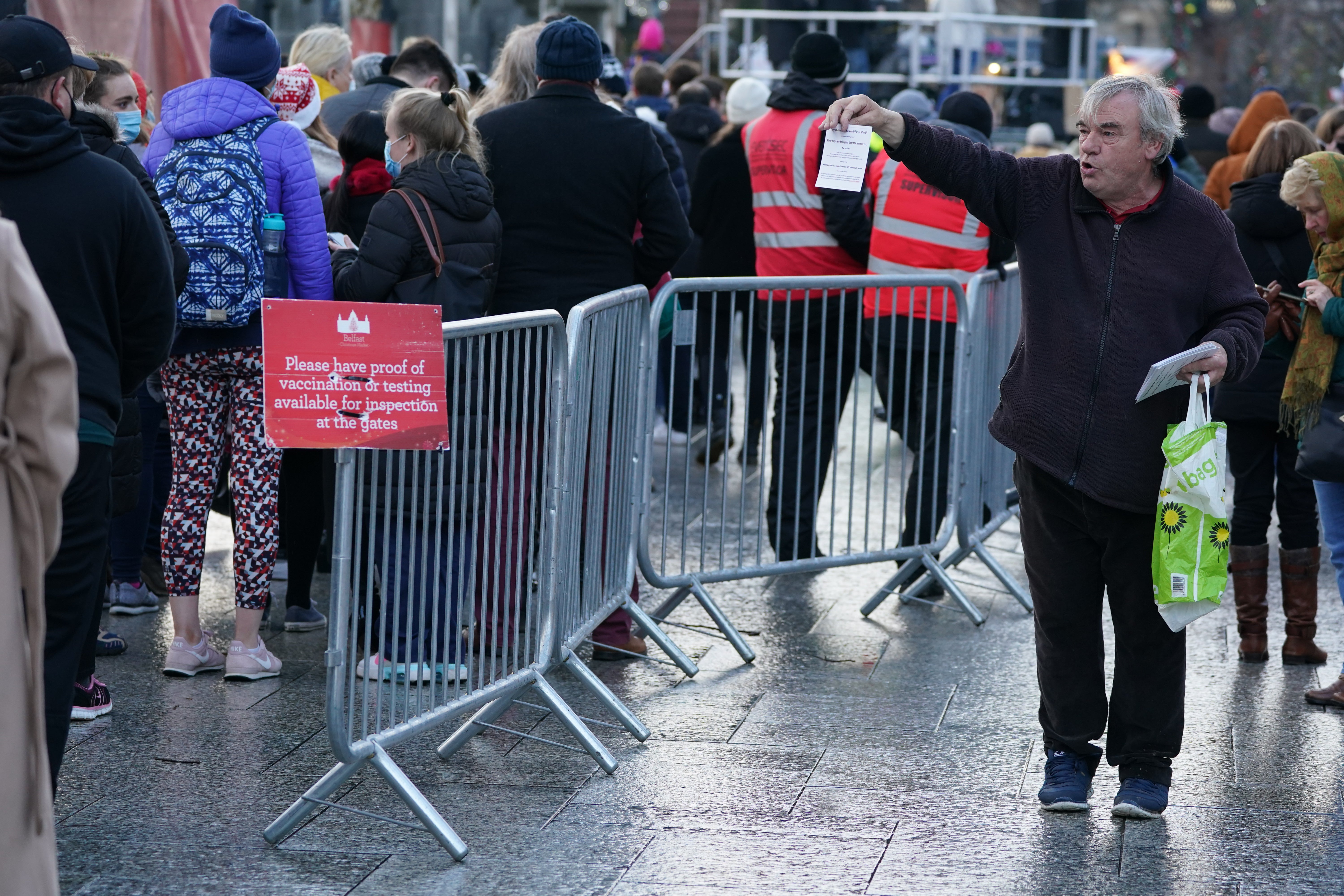 A demonstrator against the new Covid certification system holds up a sign during a protest outside Belfast City Hall as people queue to show their Covid certificates to enter the Christmas market (Brian Lawless/PA)