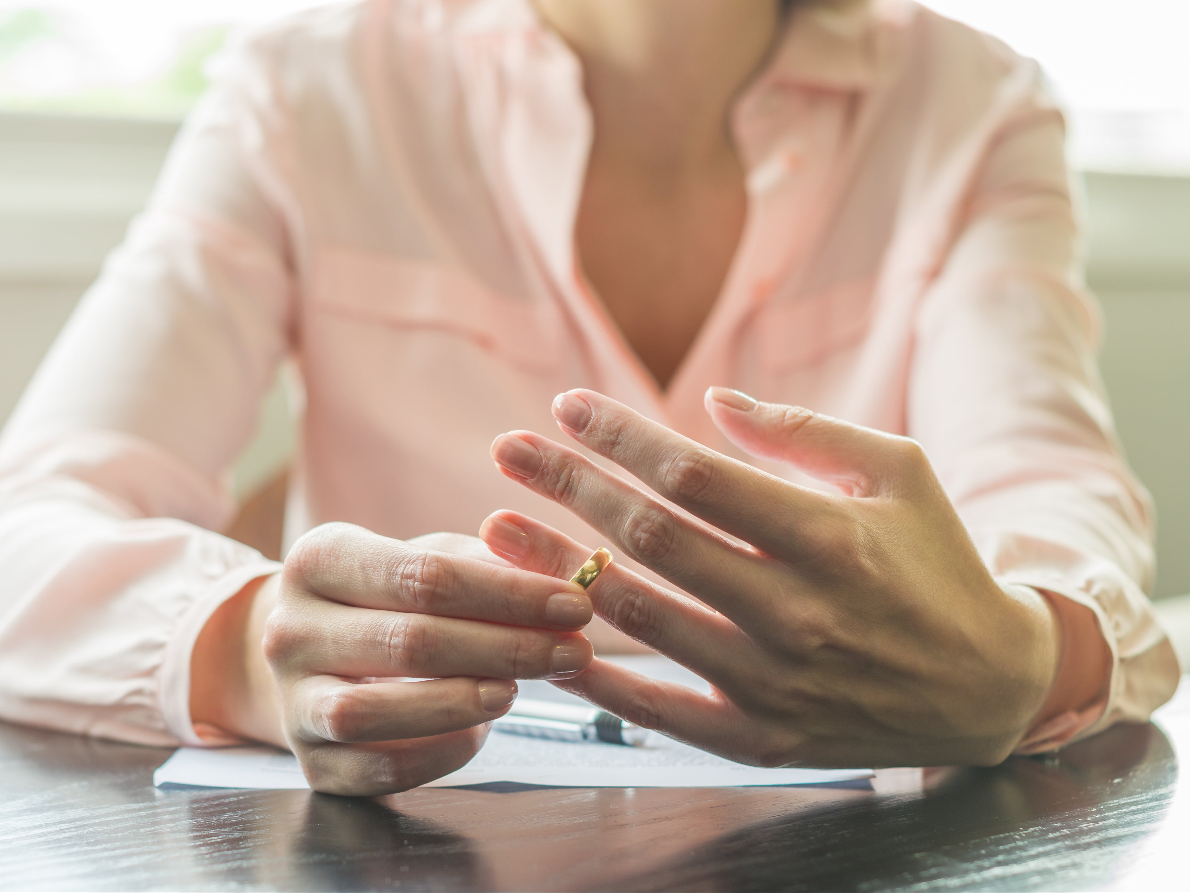 A woman removes her wedding ring after signing divorce papers