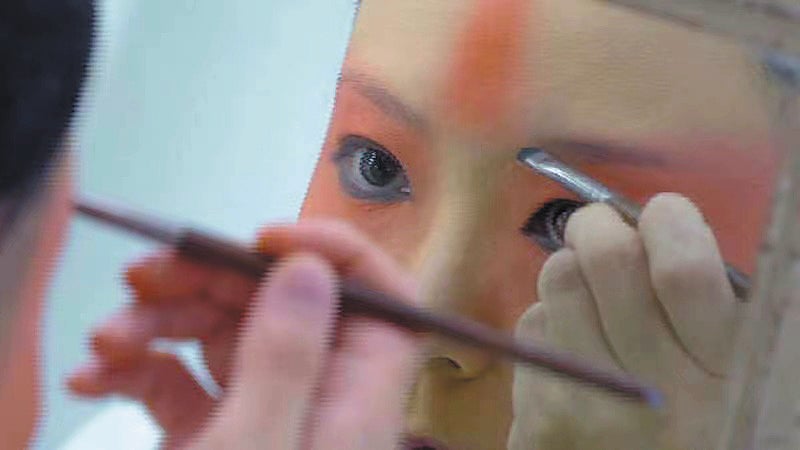 Peking Opera actress Wang Peiyu puts on make-up before playing the lead role in the production