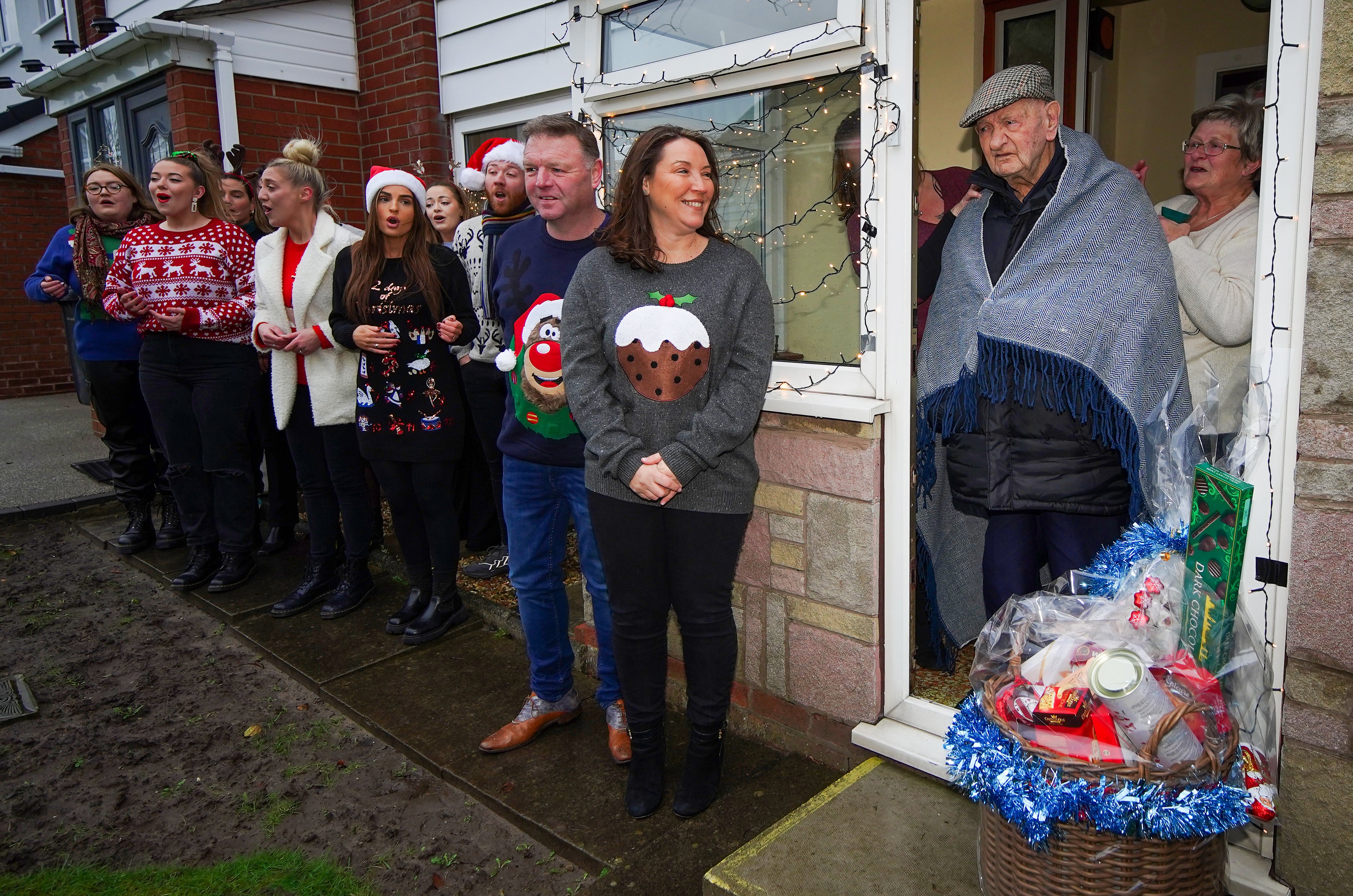 Lottery winners Sharon and Nigel Mather, who won a £12.4 million jackpot, deliver a Christmas hamper to 104-year-old war veteran Tom Beevers with the help of the LMA Choir (Peter Byrne/PA)