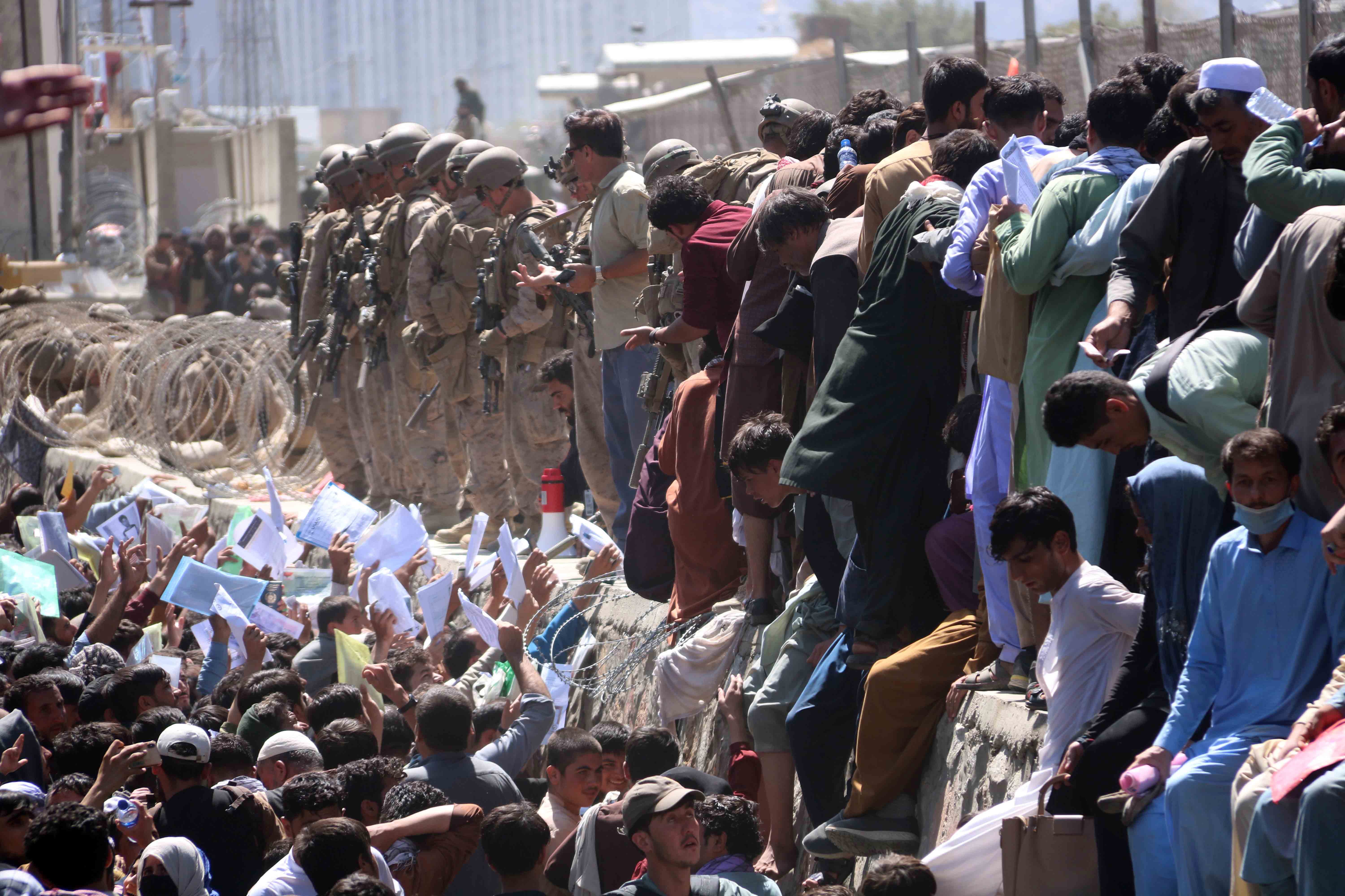 Afghans struggle to reach out and show their credentials to flee the country outside the Hamid Karzai international airport, in August 2021