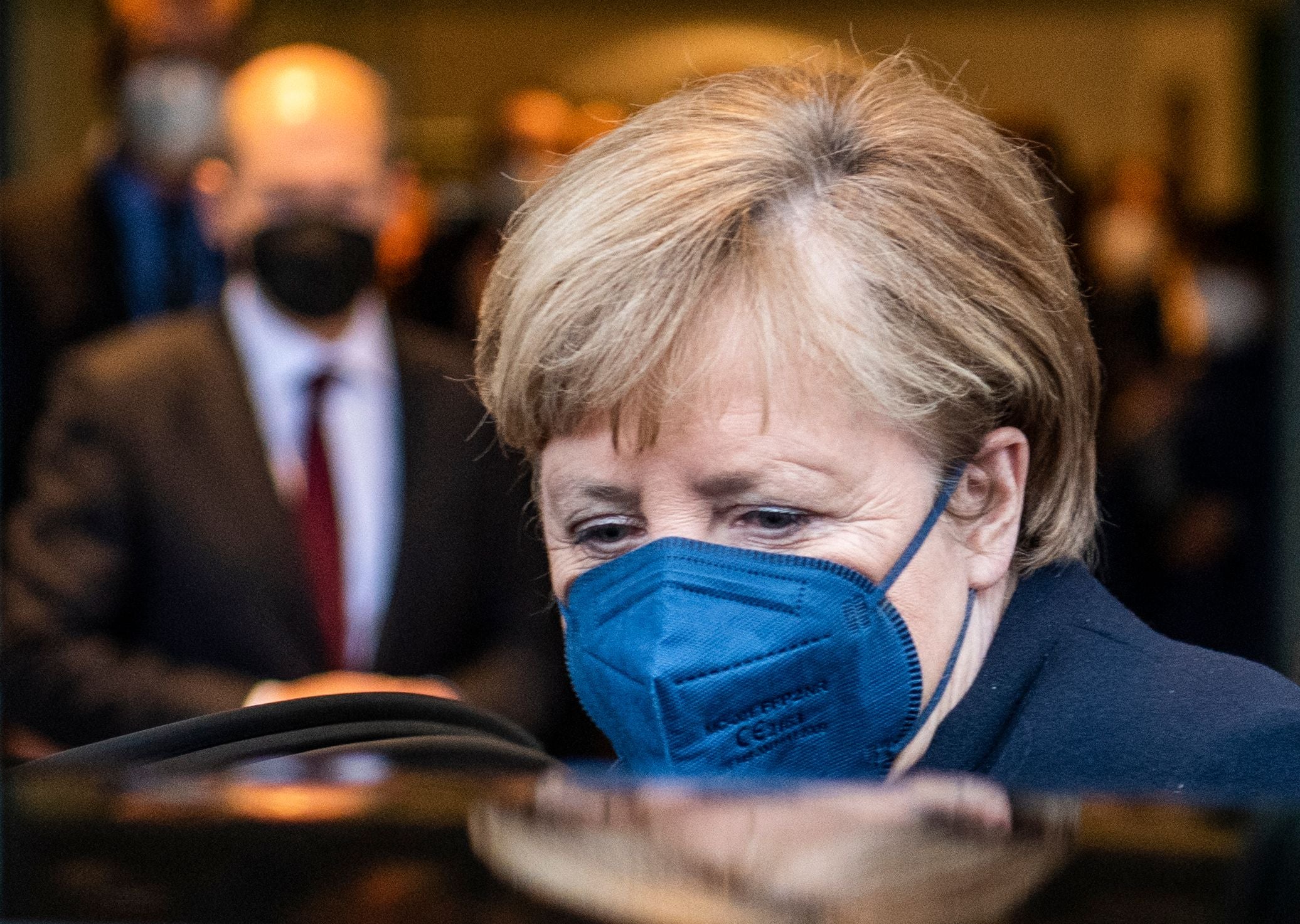 German Chancellor Olaf Scholz (background, left) looks on as his predecessor Angela Merkel gets into her car after she handed over the office to Scholz and leaves the Chancellery in Berlin