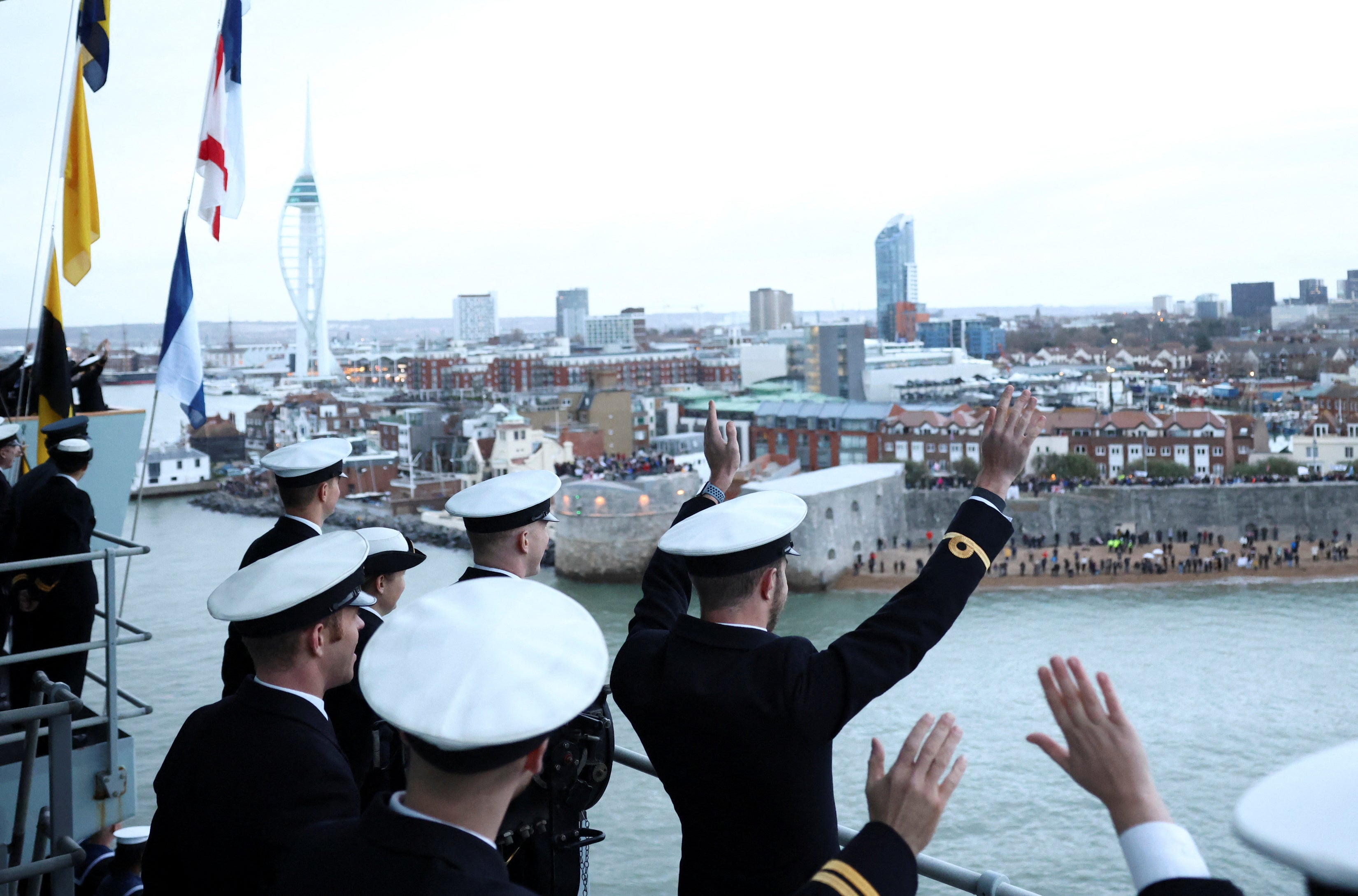 Members of the ships company wave to members of the public from the Royal Navy aircraft carrier HMS Queen Elizabeth