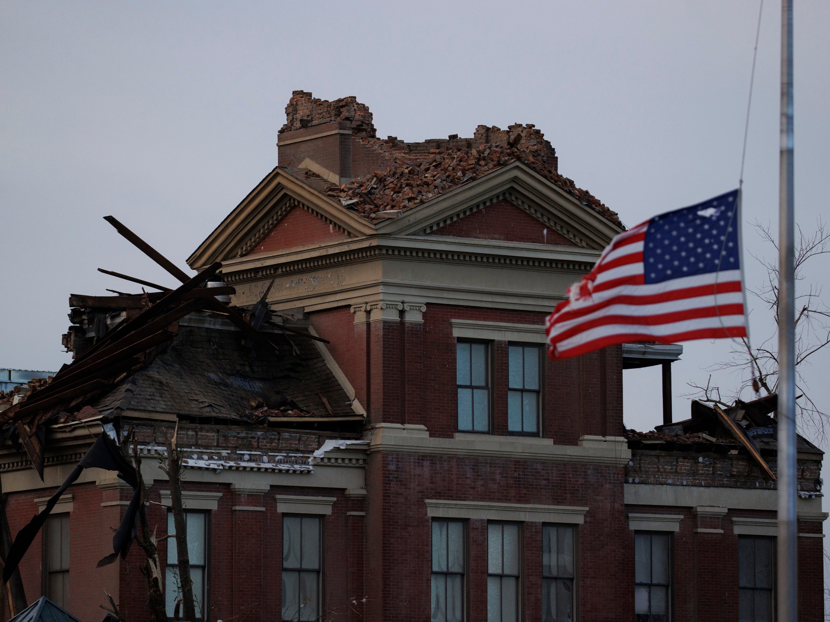 A tattered American flag flies at half-mast for Sen. Bob Dole in front of the heavy tornado-damaged courthouse on December 11, 2021 in Mayfield, Kentucky