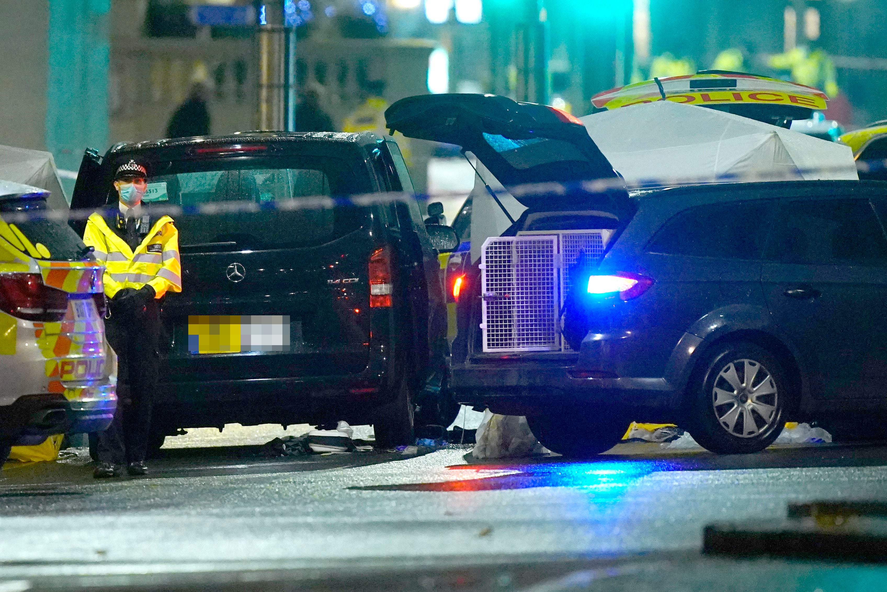 A black taxi cab and a police tent in the middle of a cordon in Kensington High Street, west London