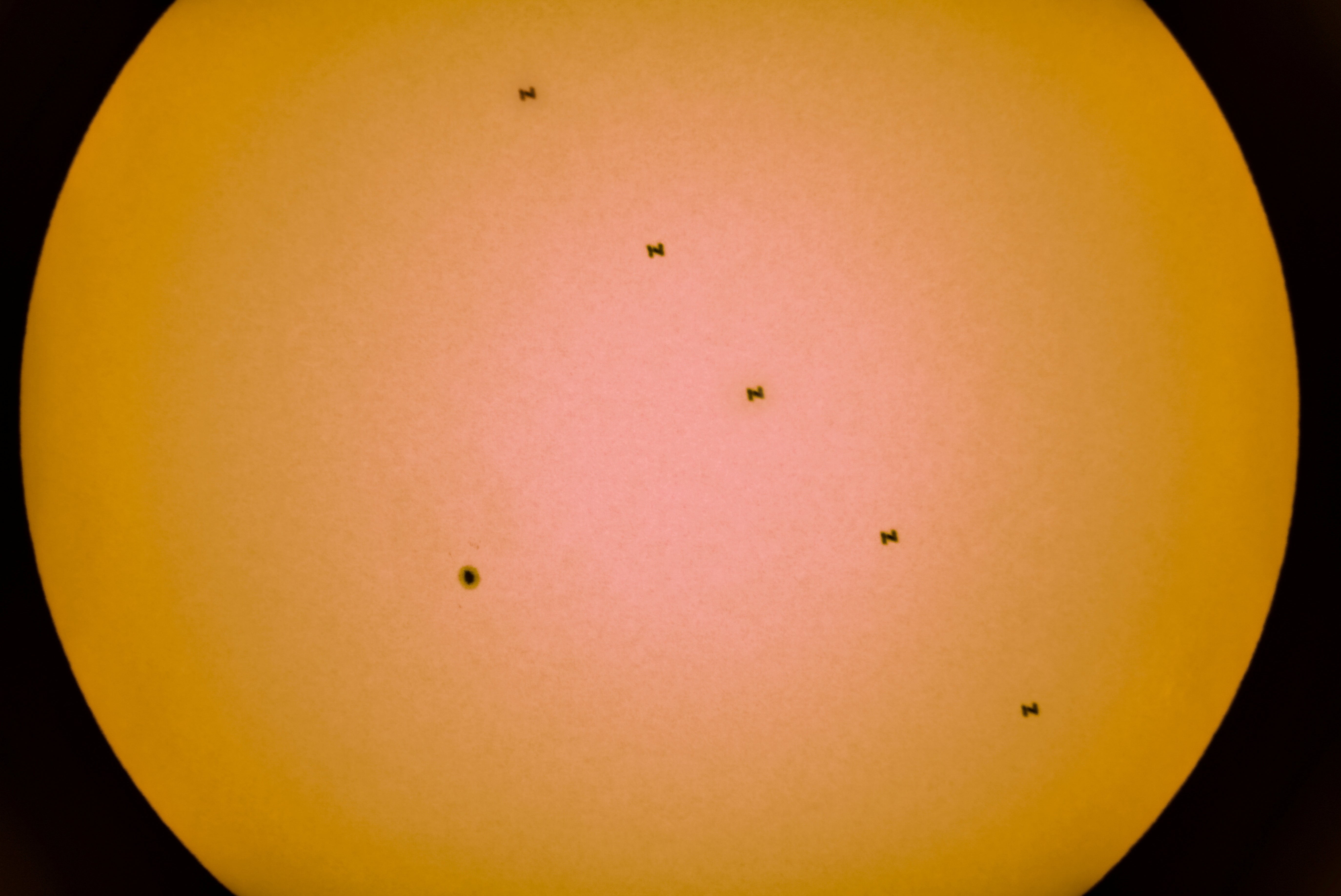 A composite image of five separate photographs taken with a fixed camera shows the International Space Station in silhouette as it passes across the Sun