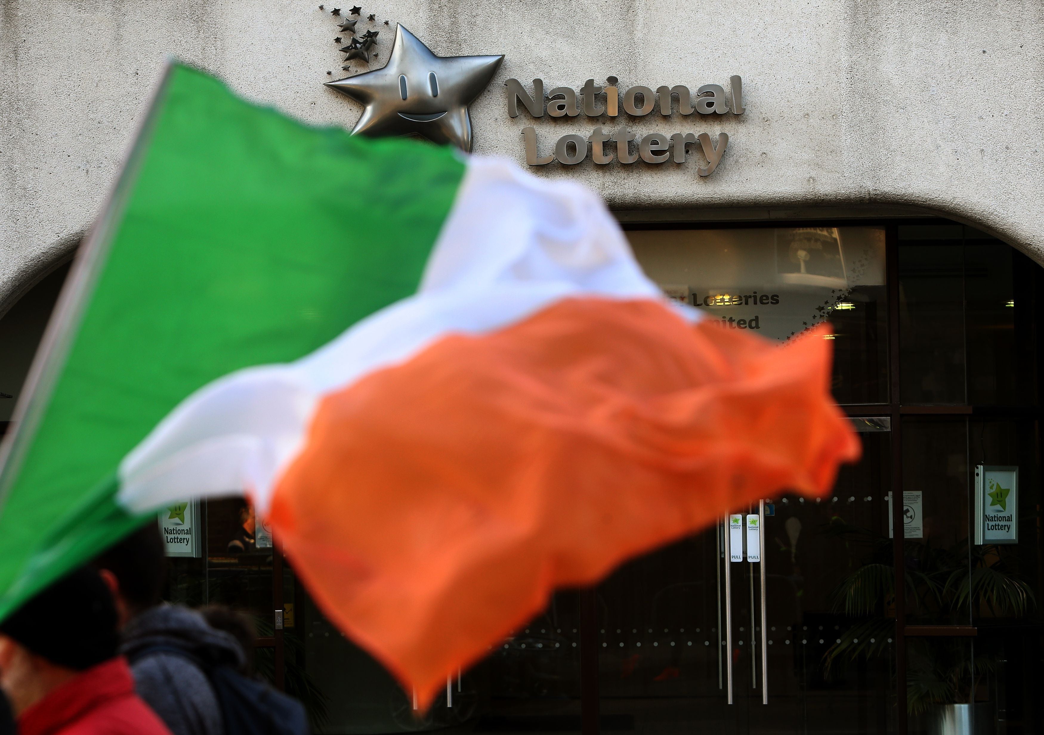 A person carrying an Irish flag walks past National Lottery Headquarters on Lower Abbey Street in Dublin (Brian Lawless/PA)