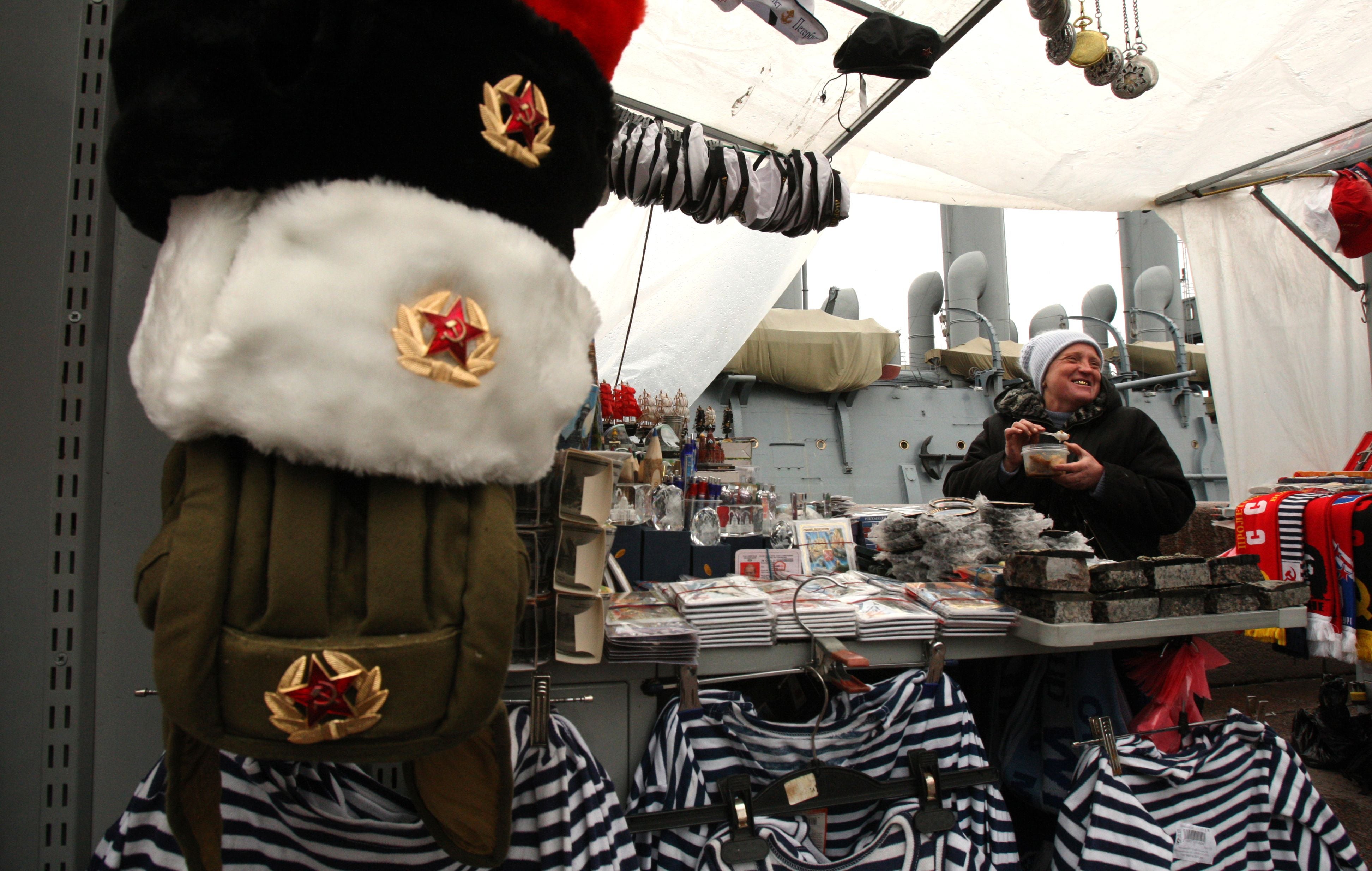 A street vendor eats lunch as she sells former Soviet Union military uniforms and gifts near the cruiser ‘Aurora’ in St Petersburg