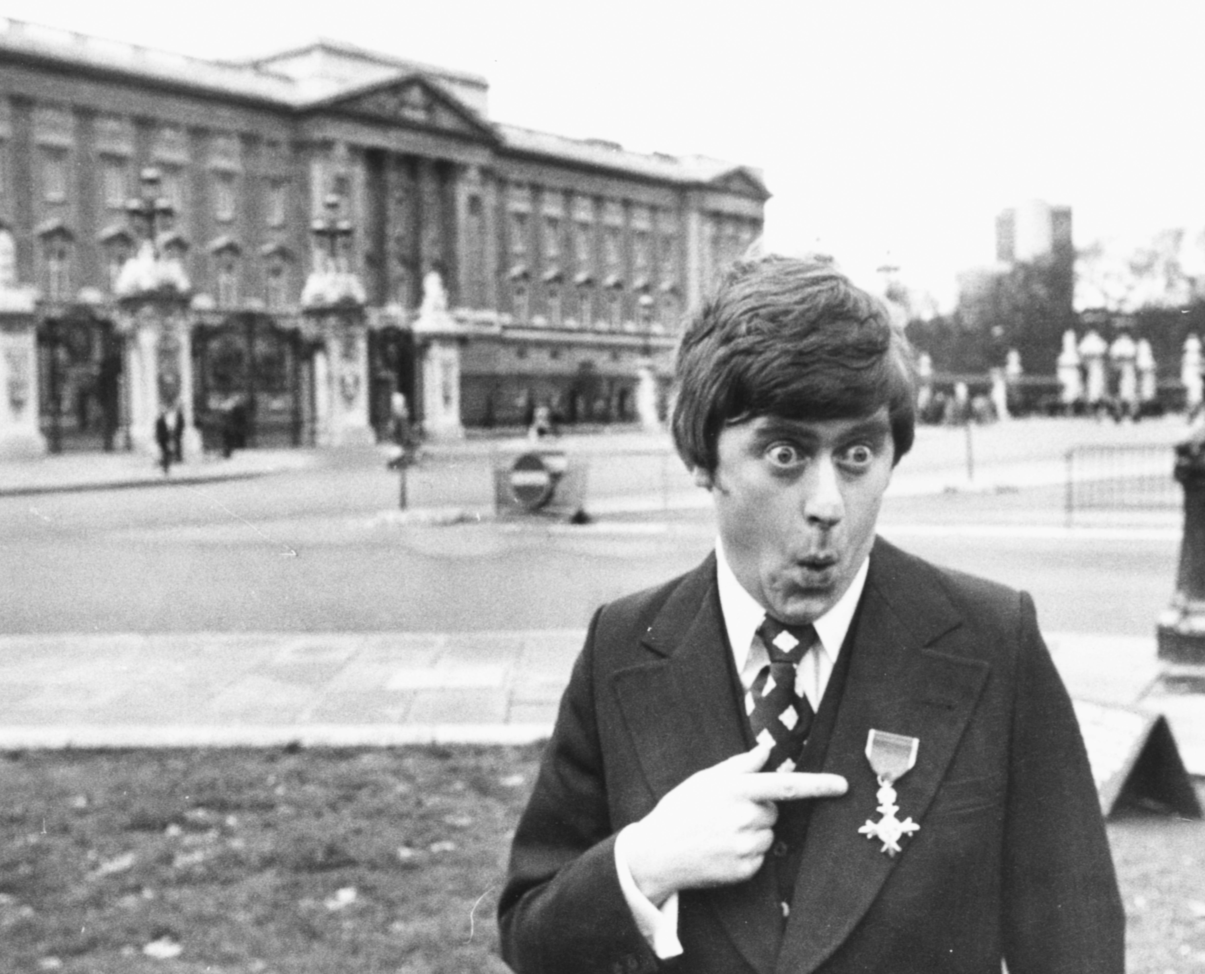 Comedian impressionist Mike Yarwood joking around outside Buckingham Palace after receiving his investiture from the Queen in 1976