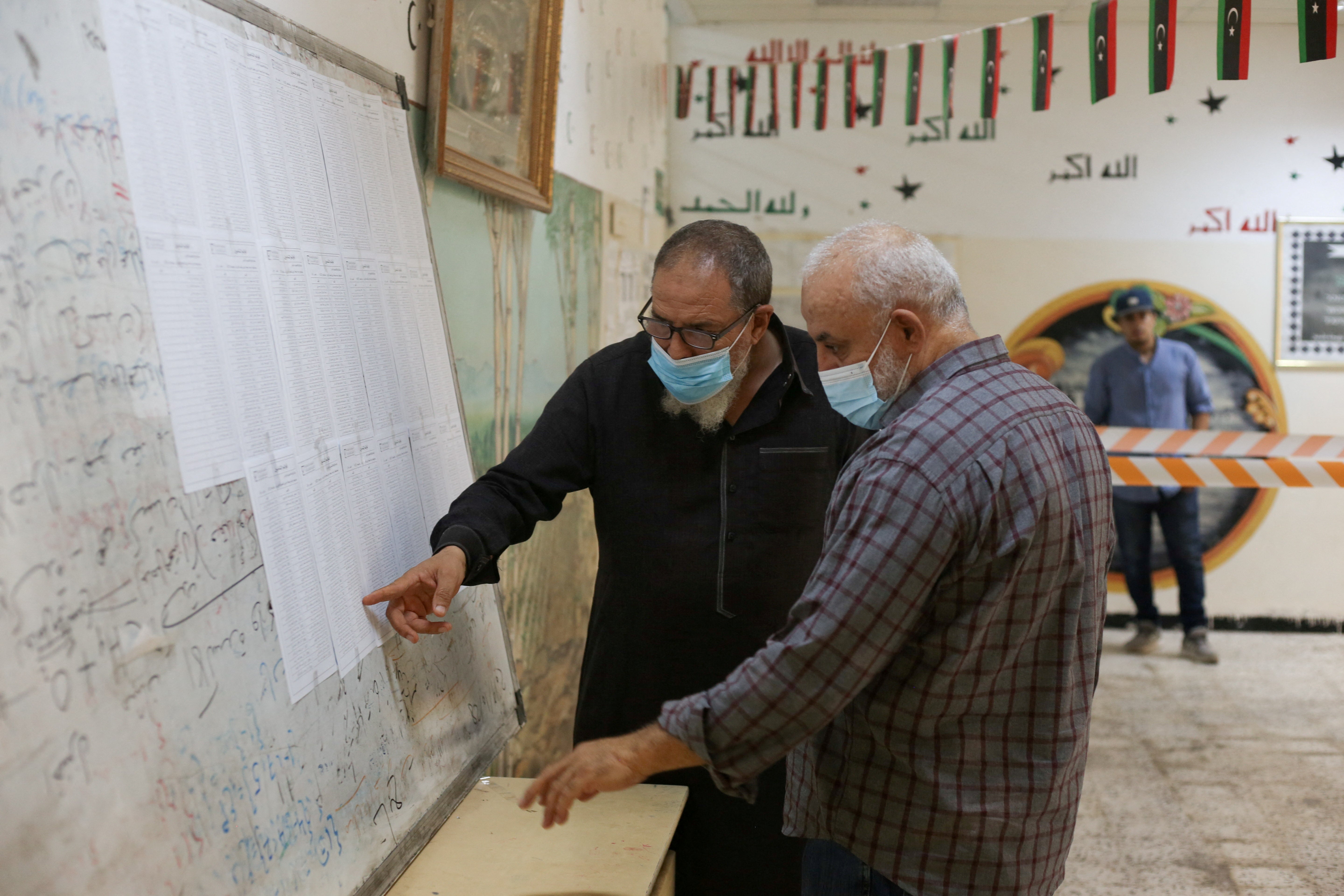 People check names to receive their voter cards inside a polling station in Tripoli