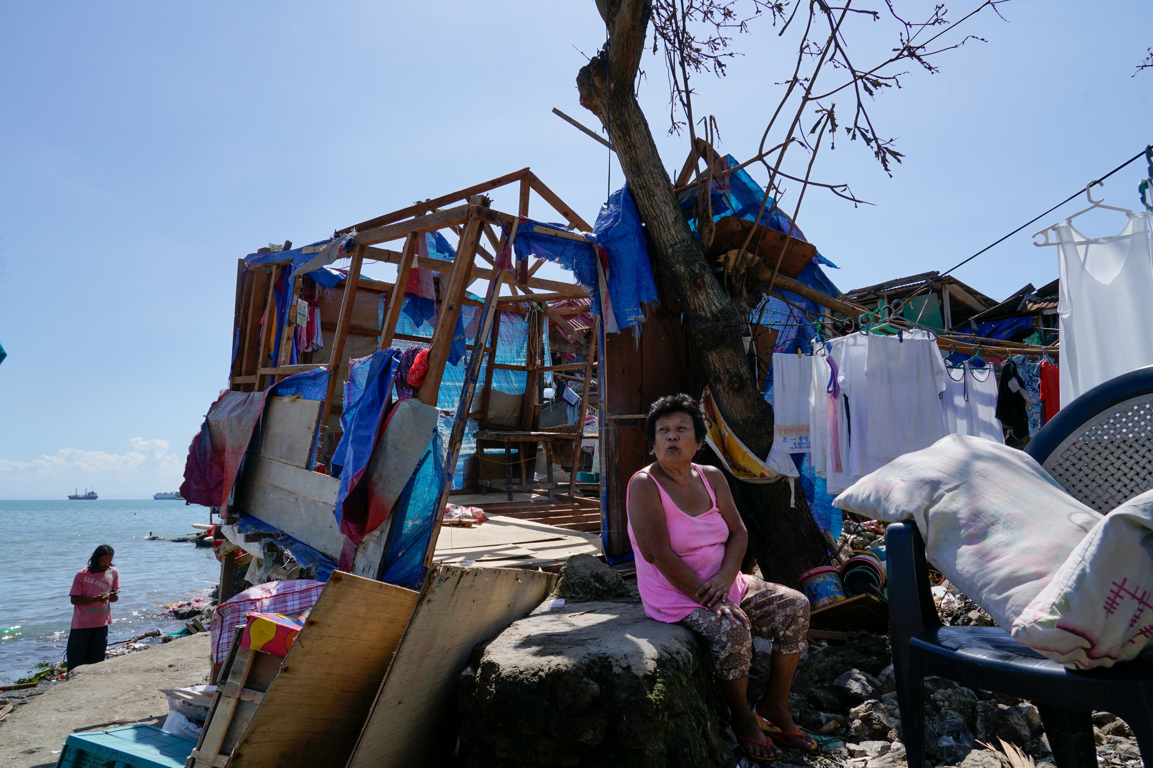 A woman sits beside damaged homes due to Typhoon Rai