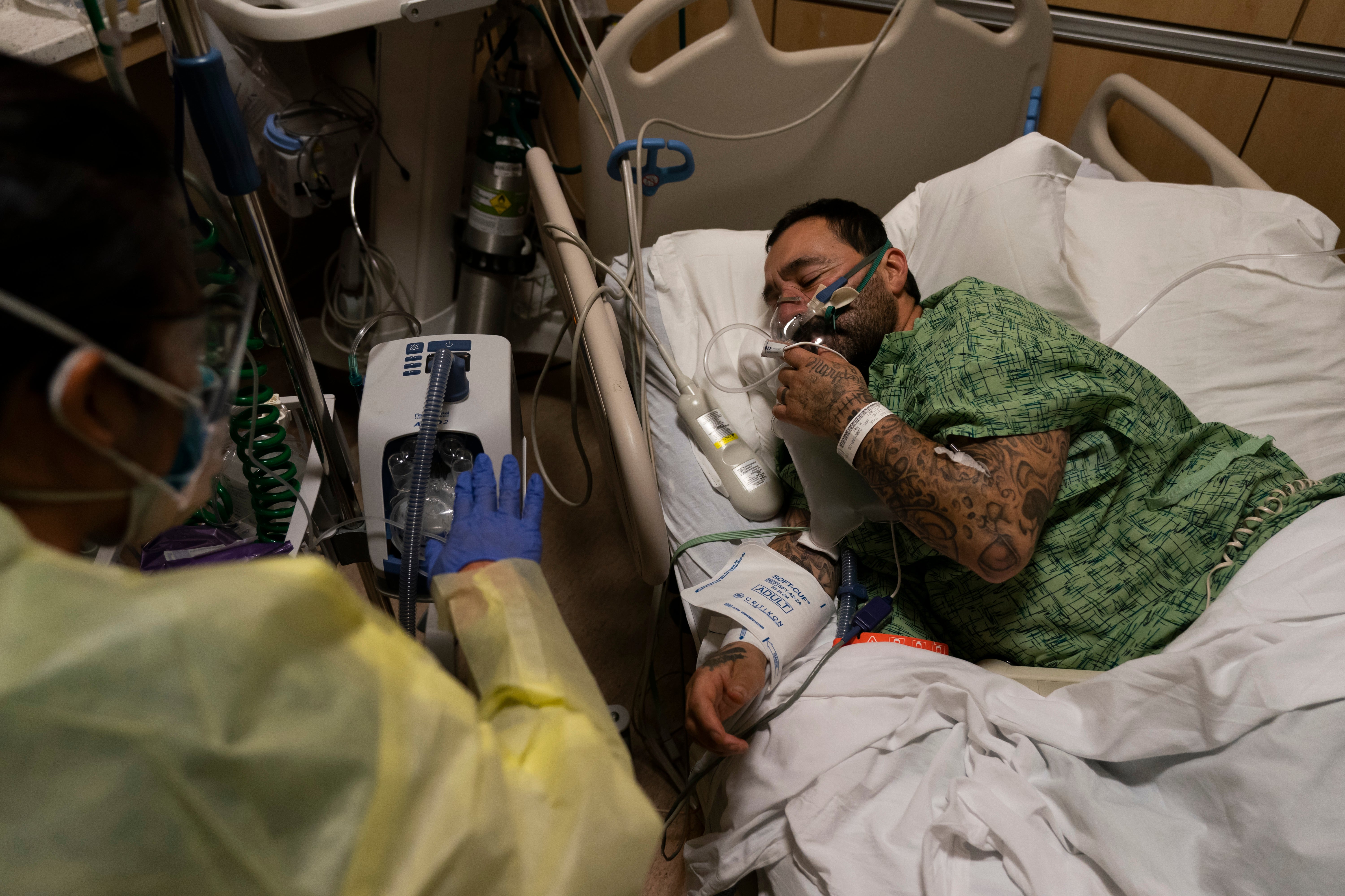 Registered nurse Emily Yu gestures to Paul Altamirano, 50, while treating him in a Covid-19 unit at Providence Holy Cross Medical Center in Los Angeles, Monday