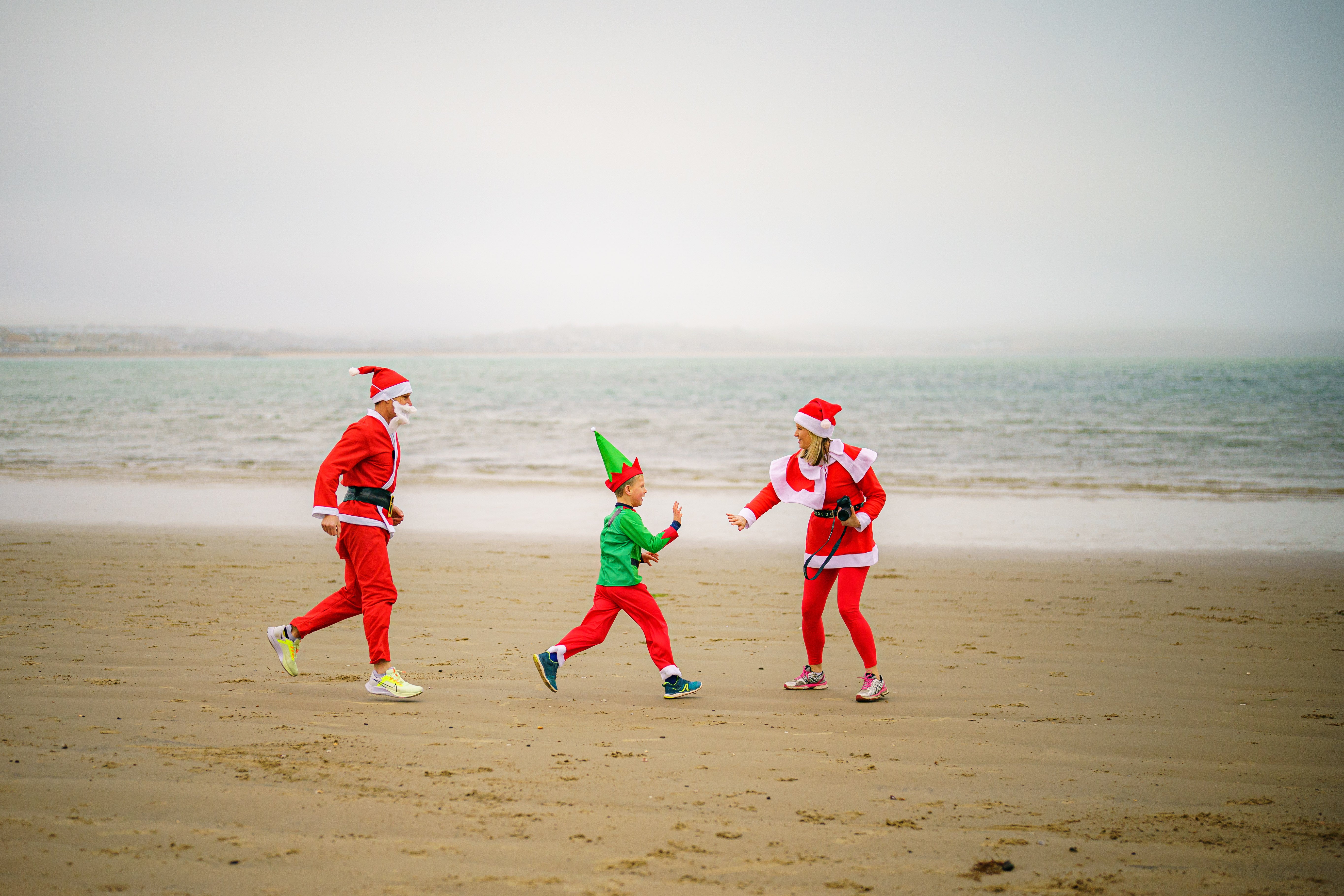 People dressed as Santa make their way along Weymouth beach (Ben Birchall/PA)