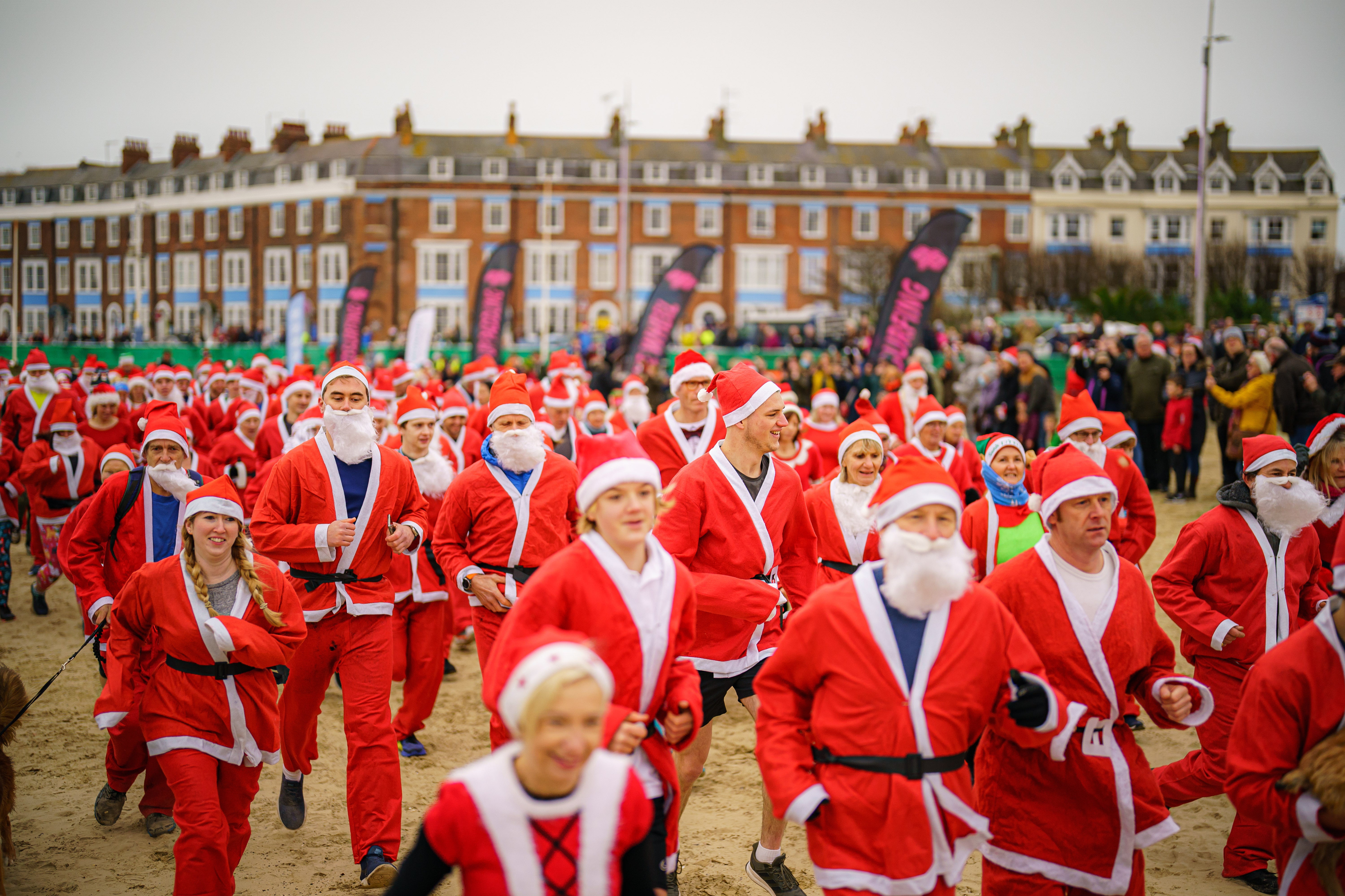 People dressed as Santa make their way along Weymouth beach (Ben Birchall/PA)