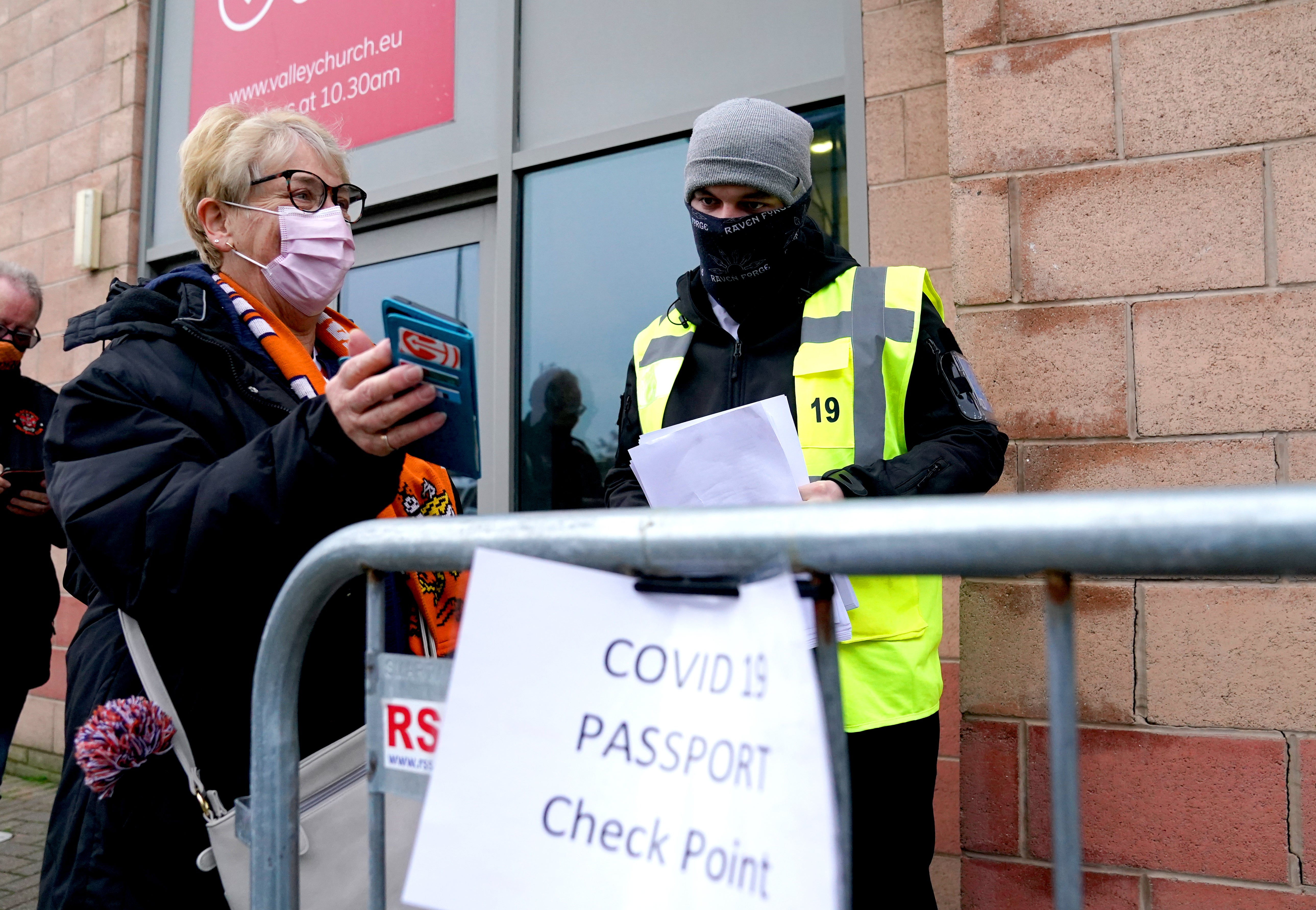 A Blackpool fan shows their Covid pass to a member of security staff at the Covid 19 passport check point ahead of the Sky Bet Championship match in Blackpool. (Martin Rickett/ PA)