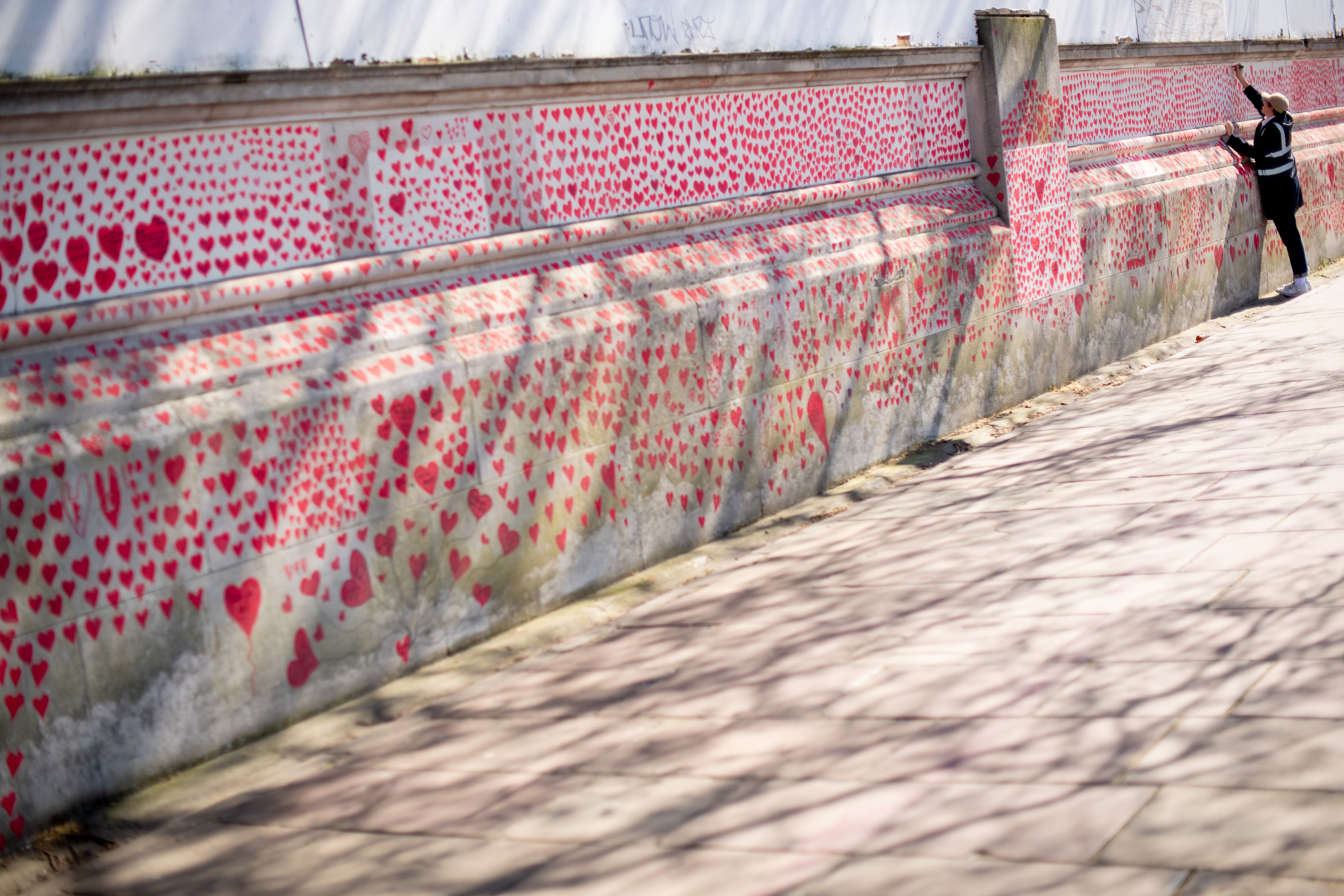 A volunteer adds hearts to the National Covid Memorial Wall in central London (Dominic Lipinski/PA)