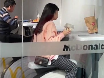 A viral TikTok shows a woman eating a burger on an exercise bike like seat