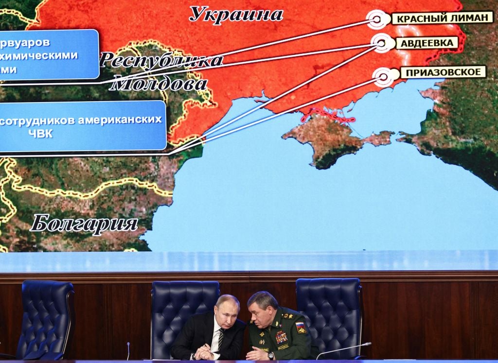 Vladimir Putin and Russian armed forces chief of the general staff Valery Gerasimov sit in front of a huge screen showing a map of Ukraine during the Defence Ministry board meeting