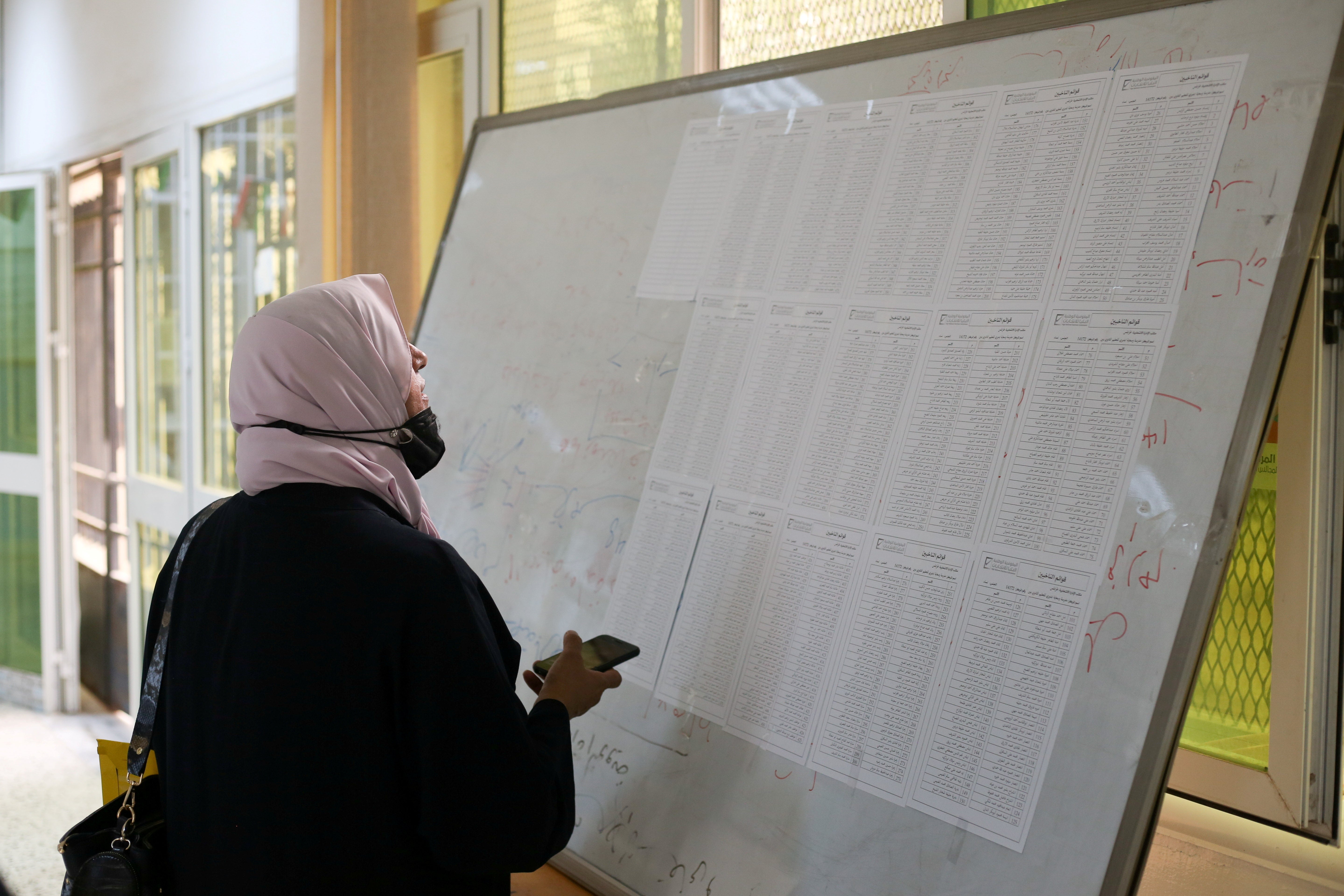 A woman checks names to receive her electoral card inside a Tripoli polling station, 8 November 2021