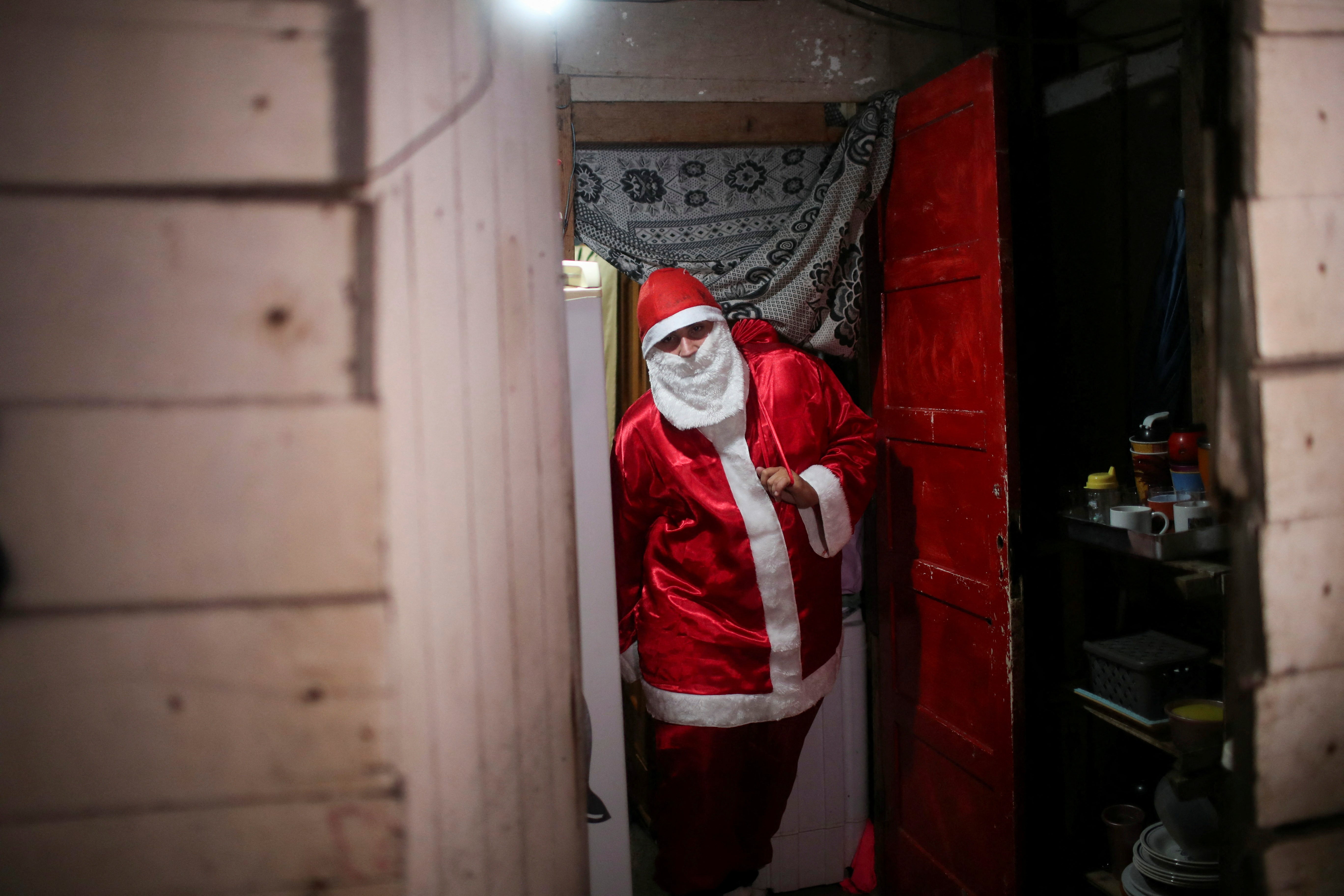 A man dressed as Santa Claus leaves the house of Shirlei Carmo da Silva, who organised the event, before distributing donated gifts