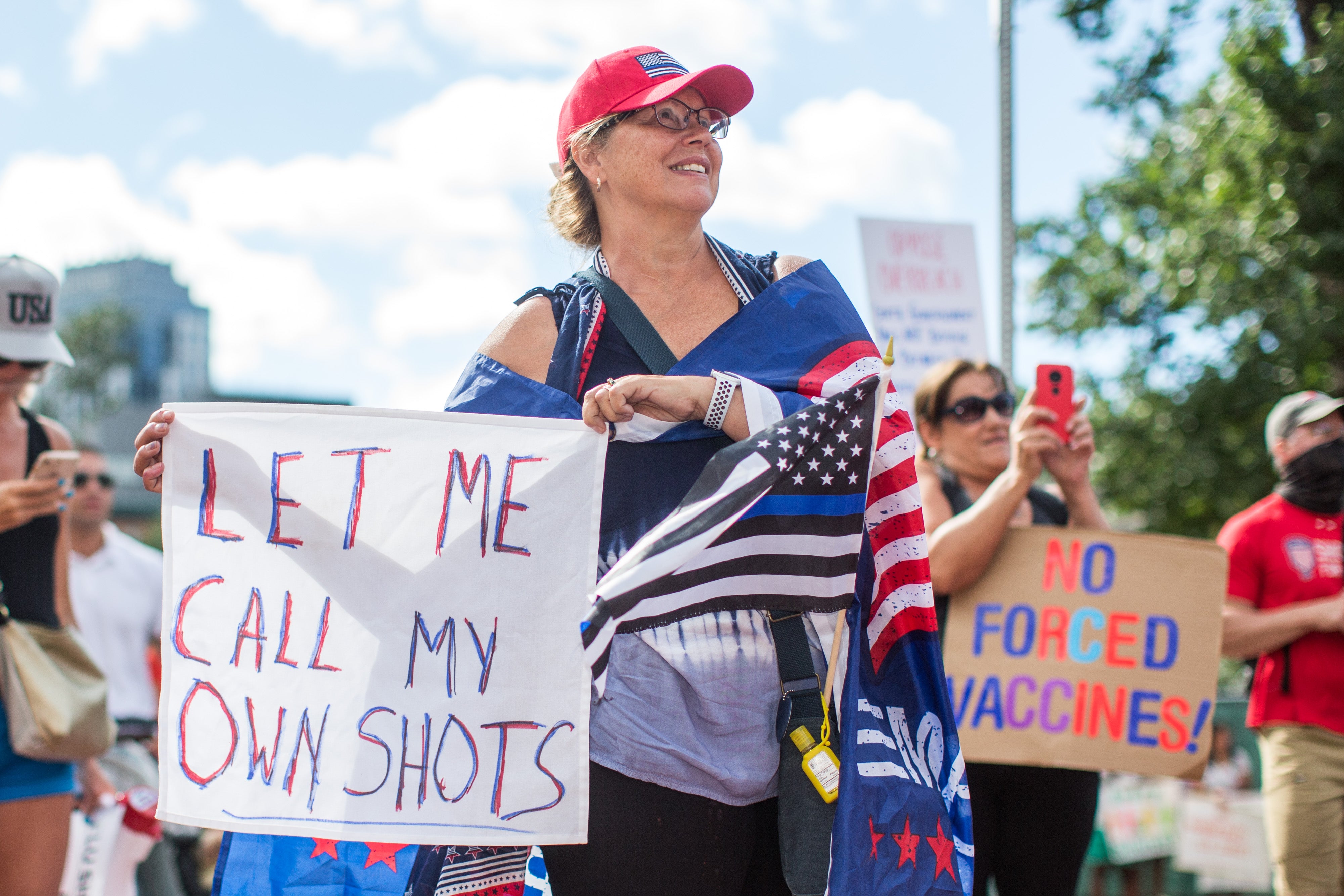 Anti-vaccine activists hold signs in front of the Massachusetts State House