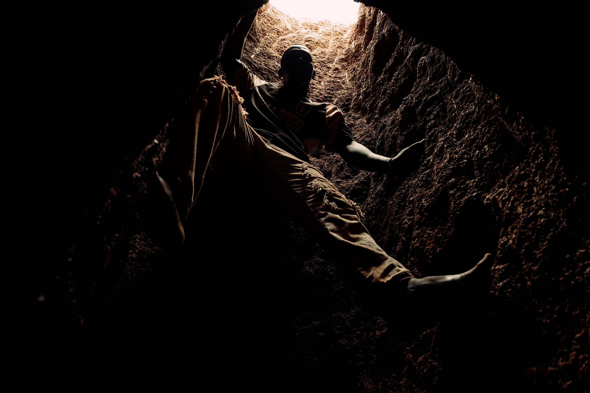 Moussa free-climbs down a 20 metre shaft, without ropes, to the bottom to extract the gold-bearing soil from the tunnels radiating underground