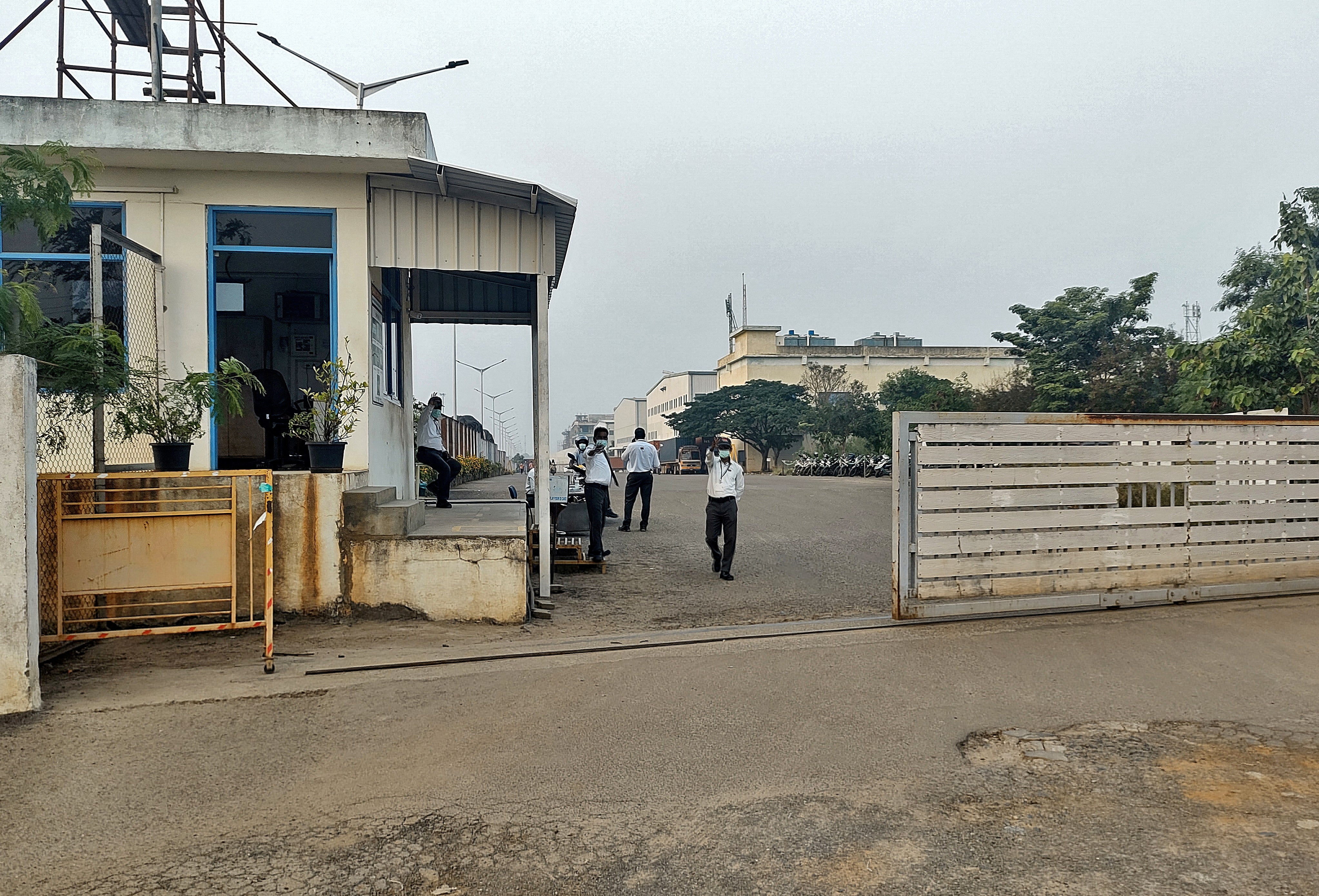 Private security guards stand at the entrance of a closed plant of Foxconn India