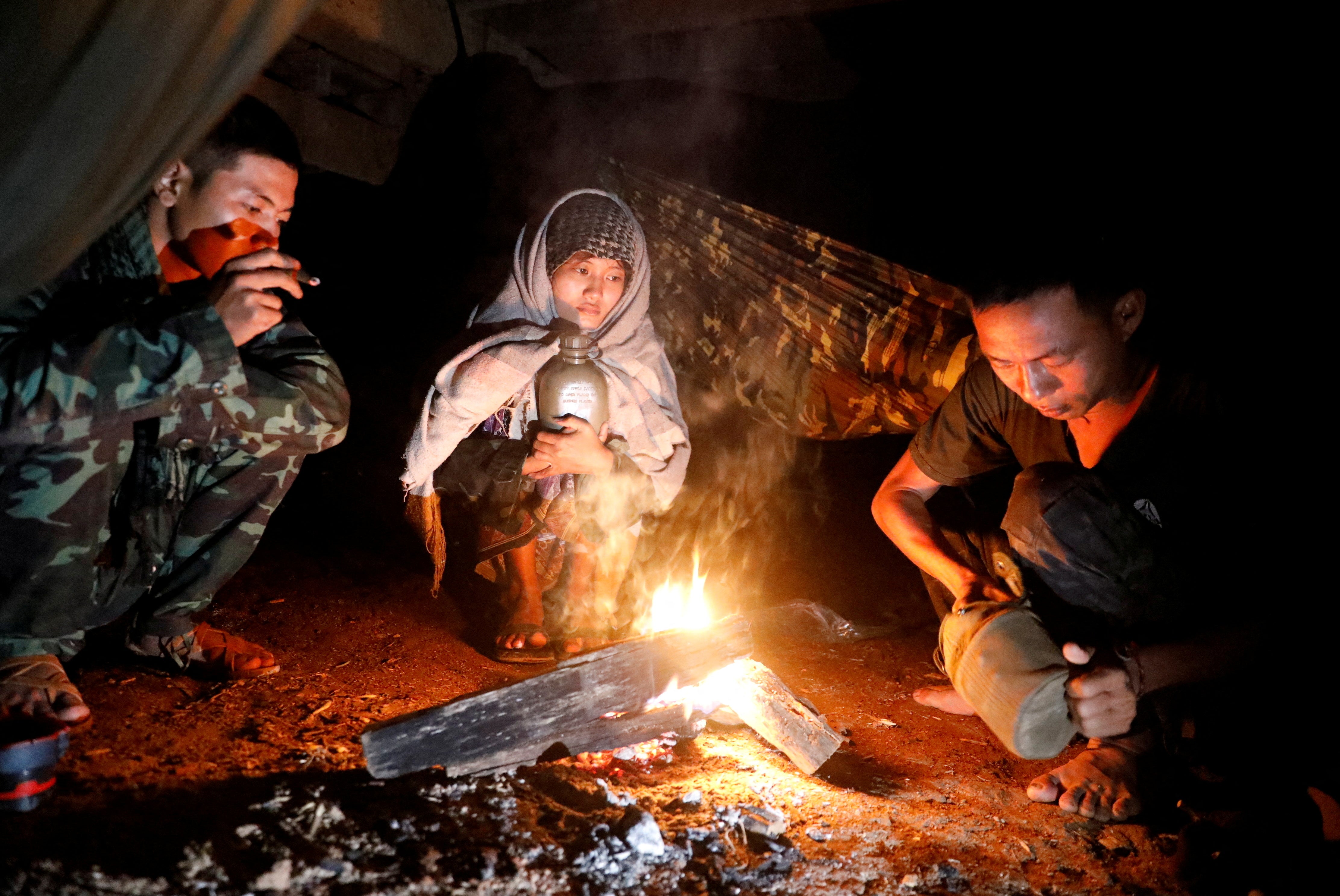 Members of the PDF sit around a fire at a training camp in an area controlled by ethnic Karen rebels