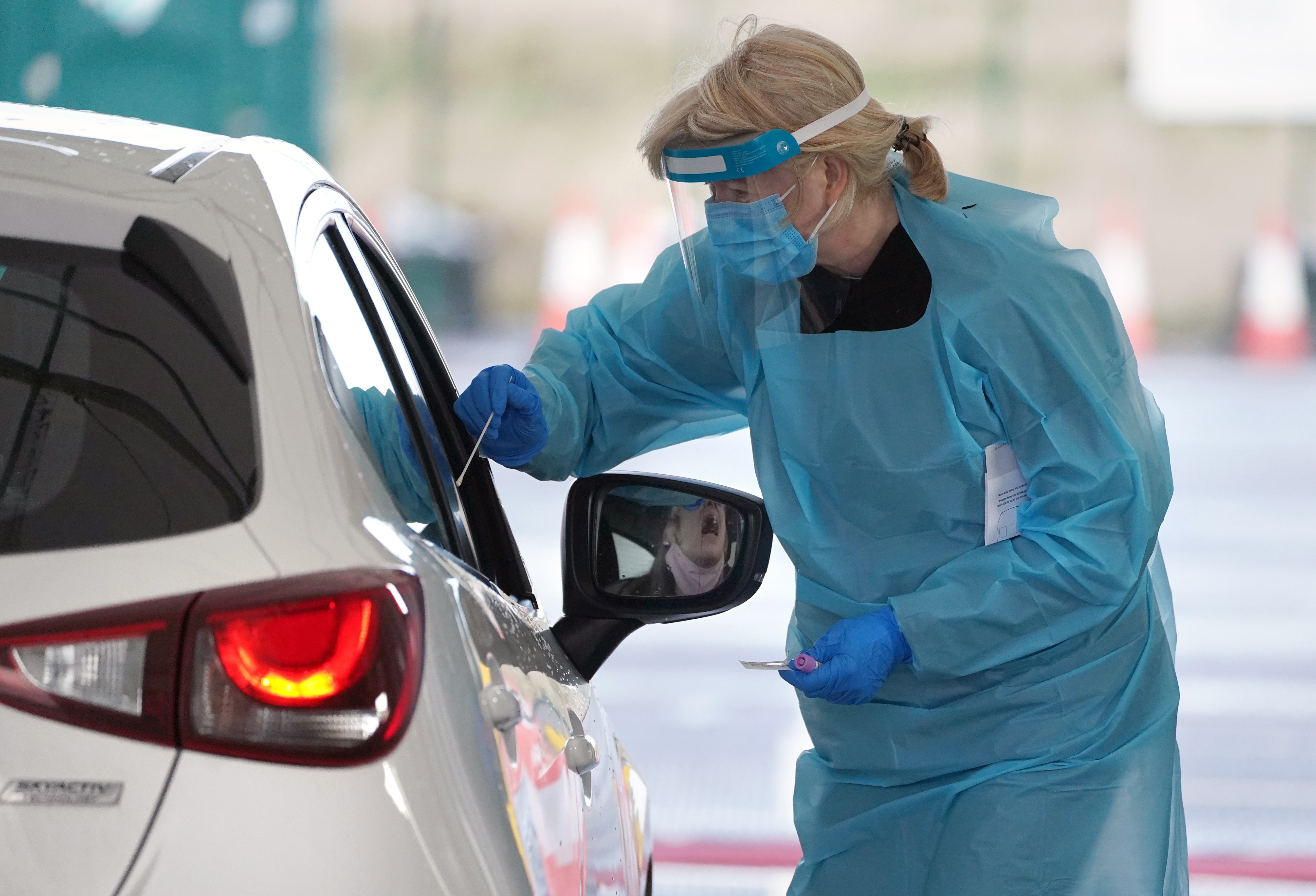 A member of staff takes a sample from a member of the public at a Covid-19 test site at Edinburgh Airport in Scotland (Andrew Milligan/PA)