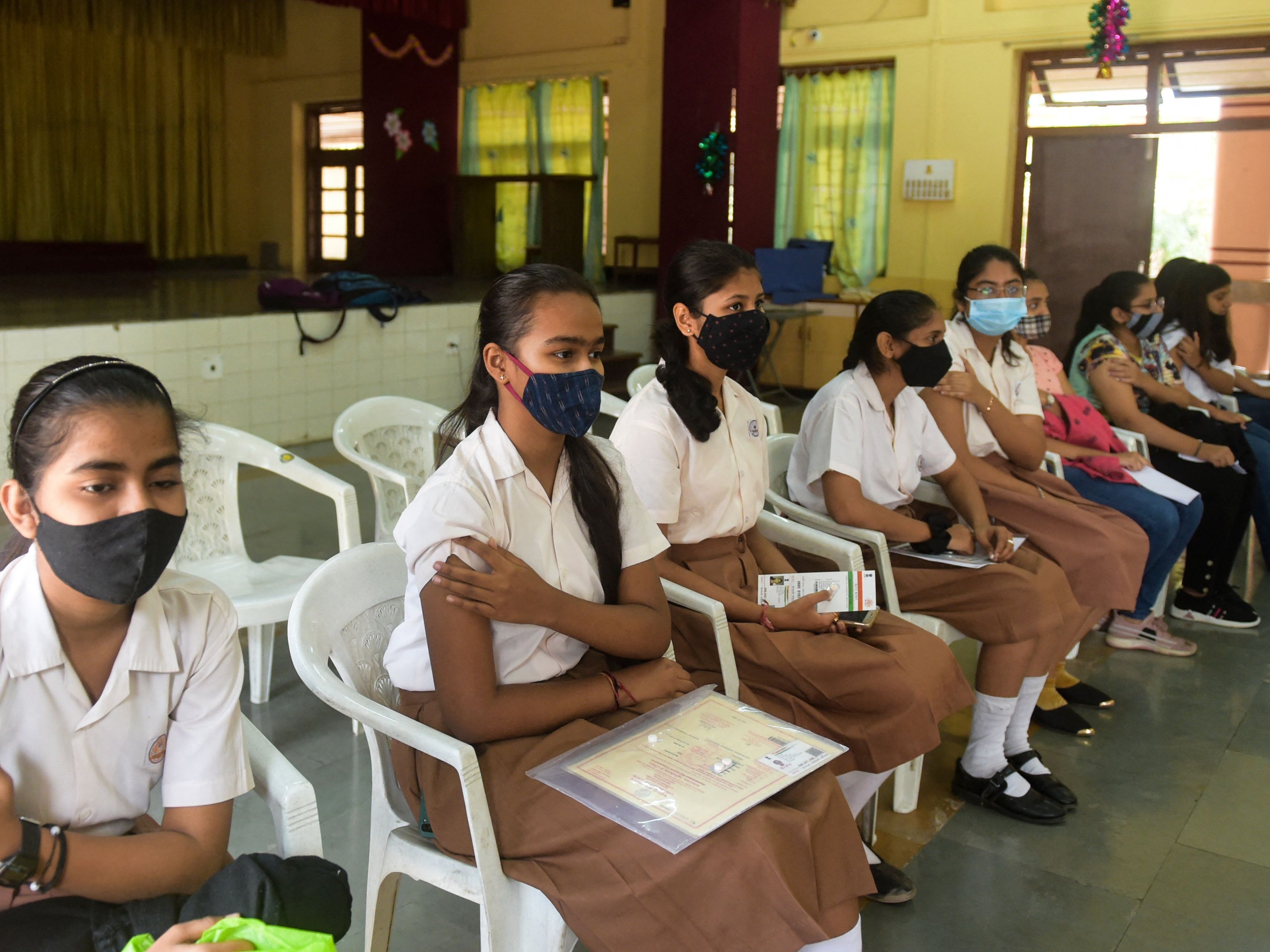 Students sit after being inoculated with a dose of the Covaxin against Covid-19 during a vaccination drive for people in the 15-18 age group at a high school in Ahmedabad on 3 January 2022